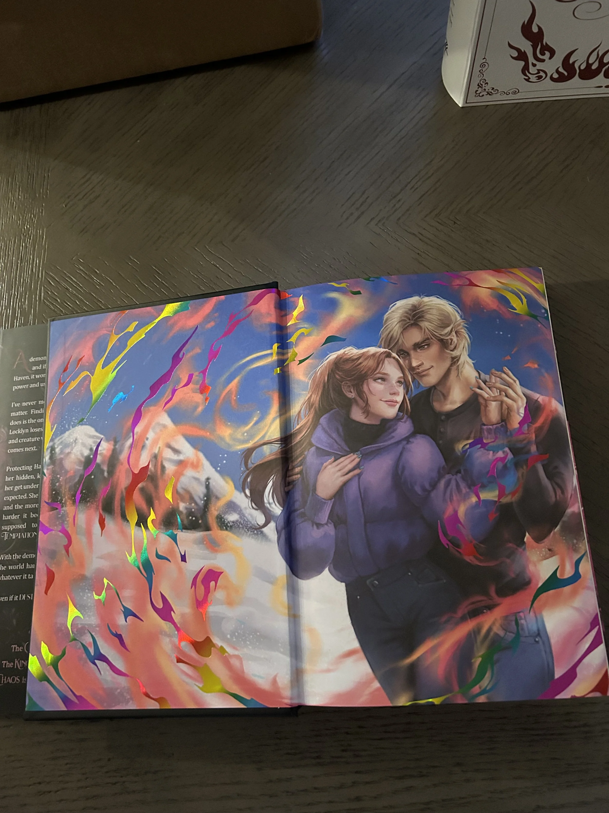 Illustrated Queen of Chaos endpapers featuring a red-haired woman and blond man surrounded by swirling pink, orange and blue fantasy artwork.