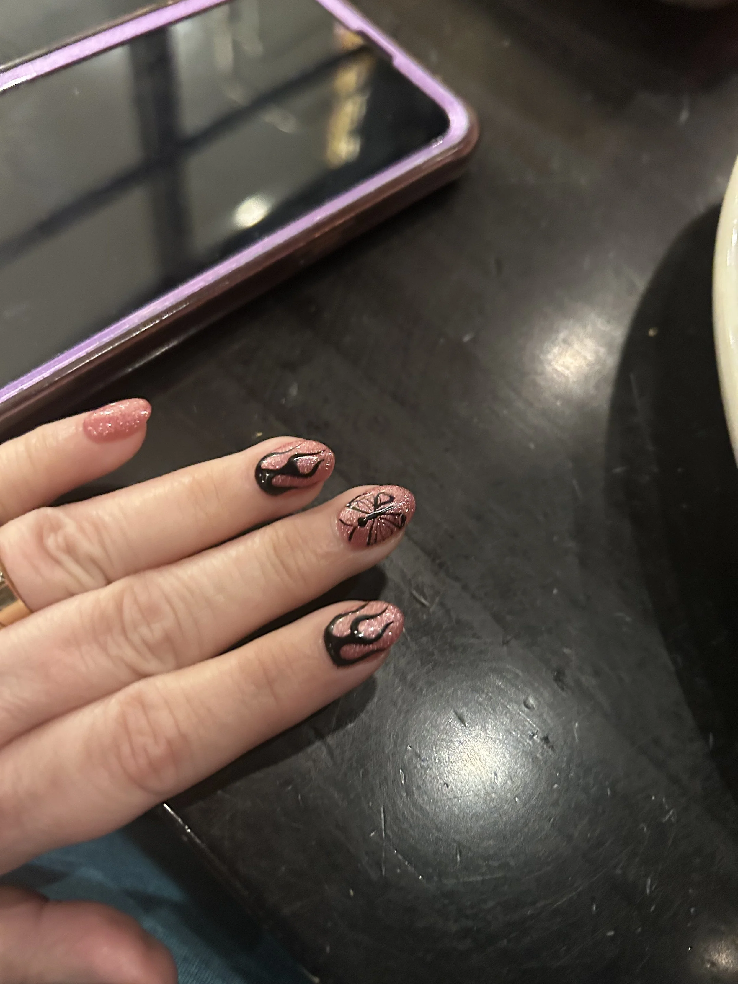 Pink glitter manicure with black butterfly and flame nail are inspired by Queen of Chaos by Julie Hall.