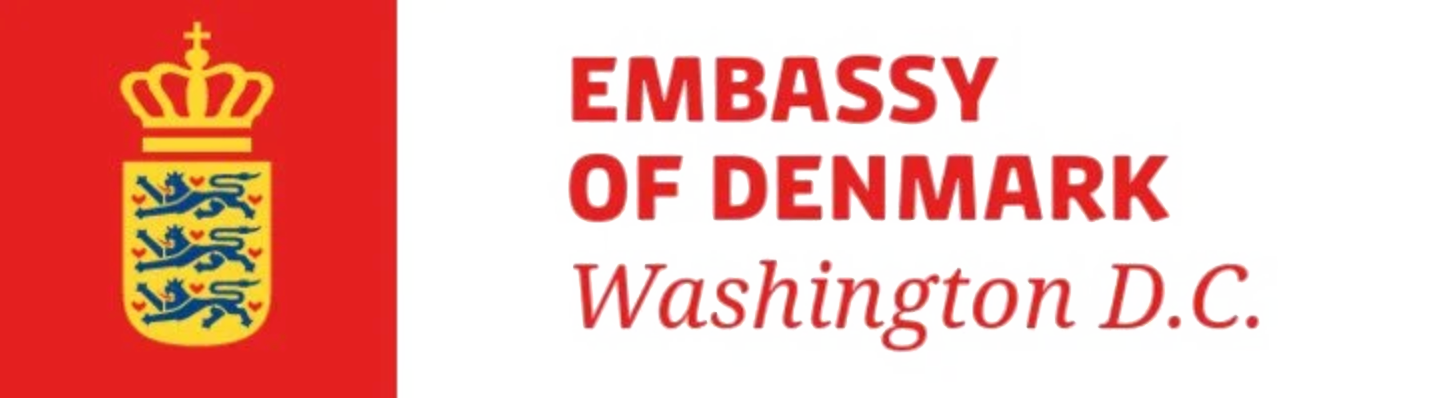 Logo of the Embassy of Denmark in Washington D.C., featuring Denmark's coat of arms with three blue lions and nine red hearts on a yellow shield, with a crown on top, and text in red and black.