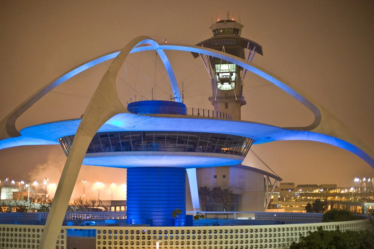 Night view of the San Francisco International Airport air traffic control tower with futuristic architecture, illuminated by blue lights.