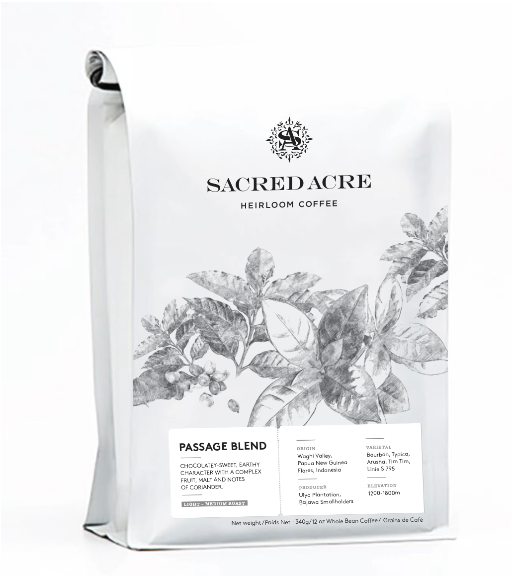 White coffee bag labeled Sacred Acre Heirloom Coffee with black and white illustration of coffee plants, and details about the flavor profile, origin, variety, and elevation.
