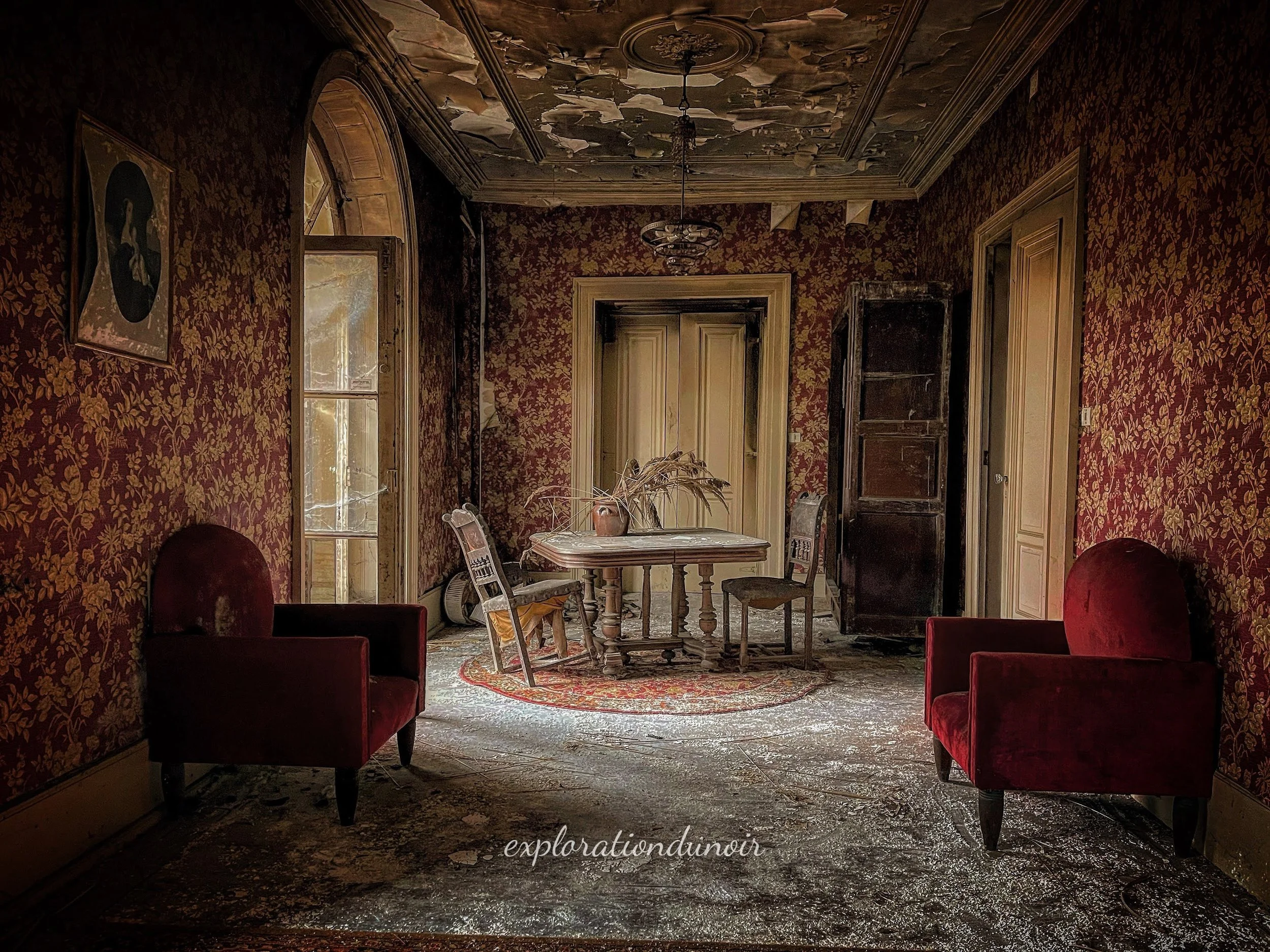 Pièce abandonnée avec papier peint rouge et mobilier ancien