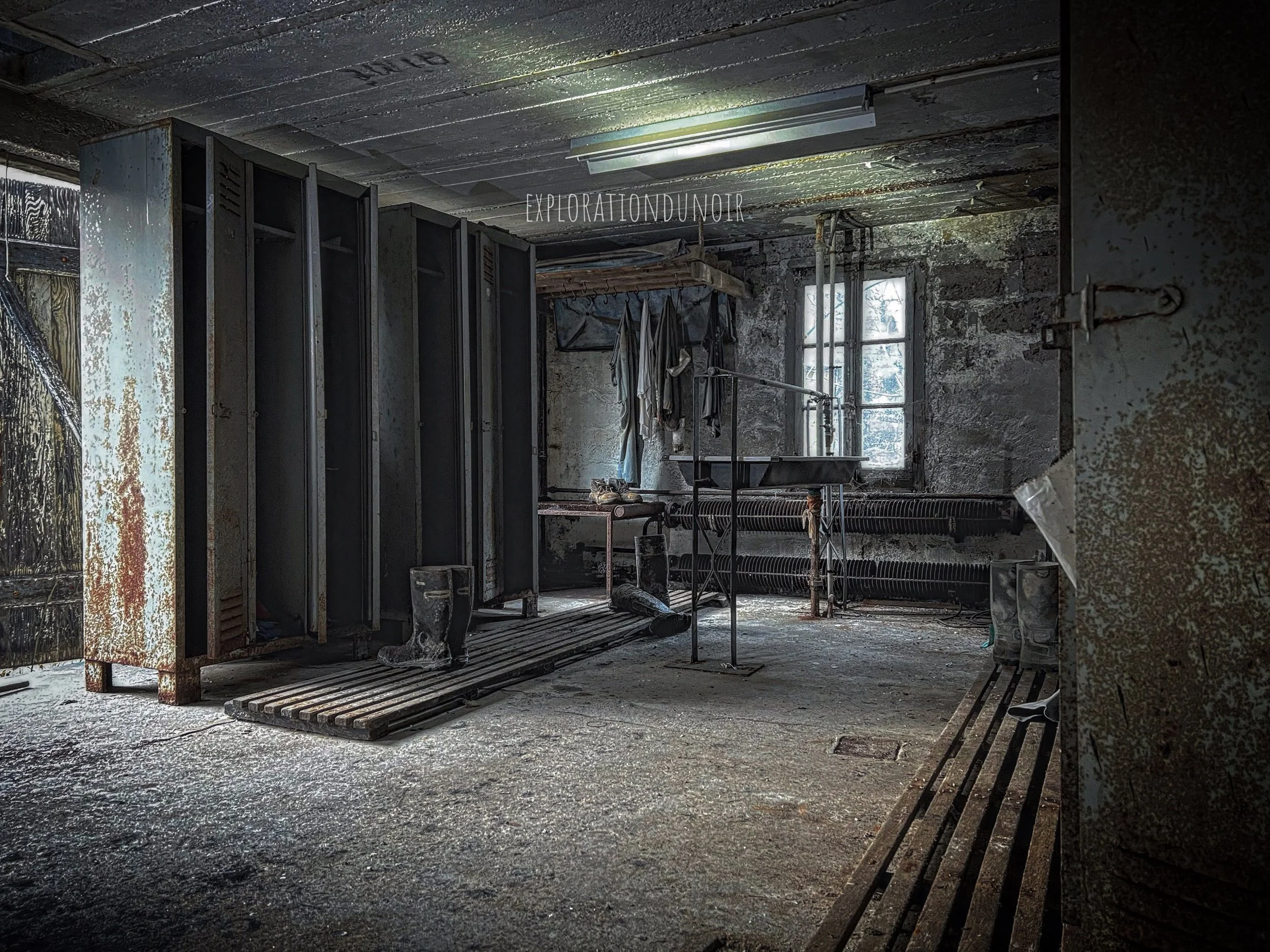 Ancienne usine abandonnée avec vestiaires métalliques et fenêtres brisées