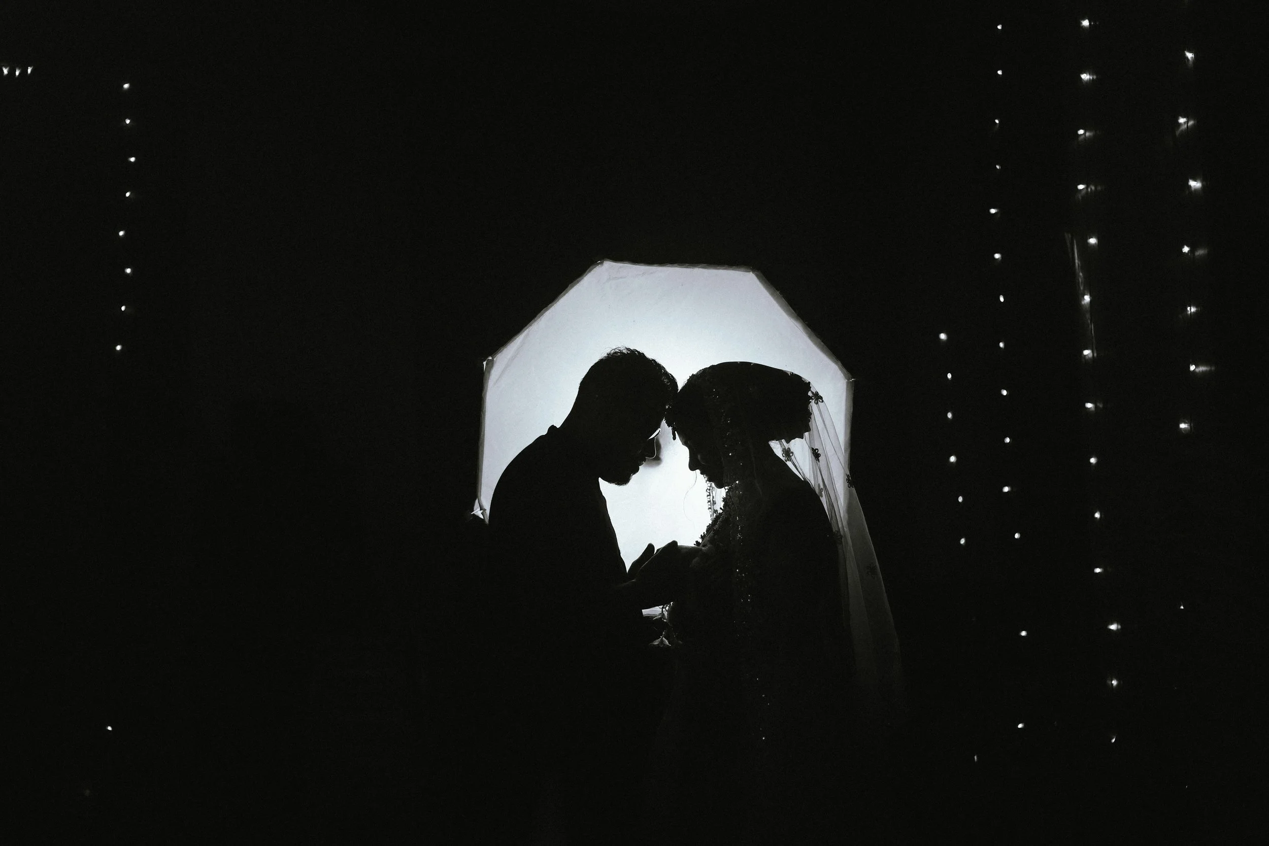 Couple de mariés enlacé lors d’une réception de mariage, photographie en noir et blanc.