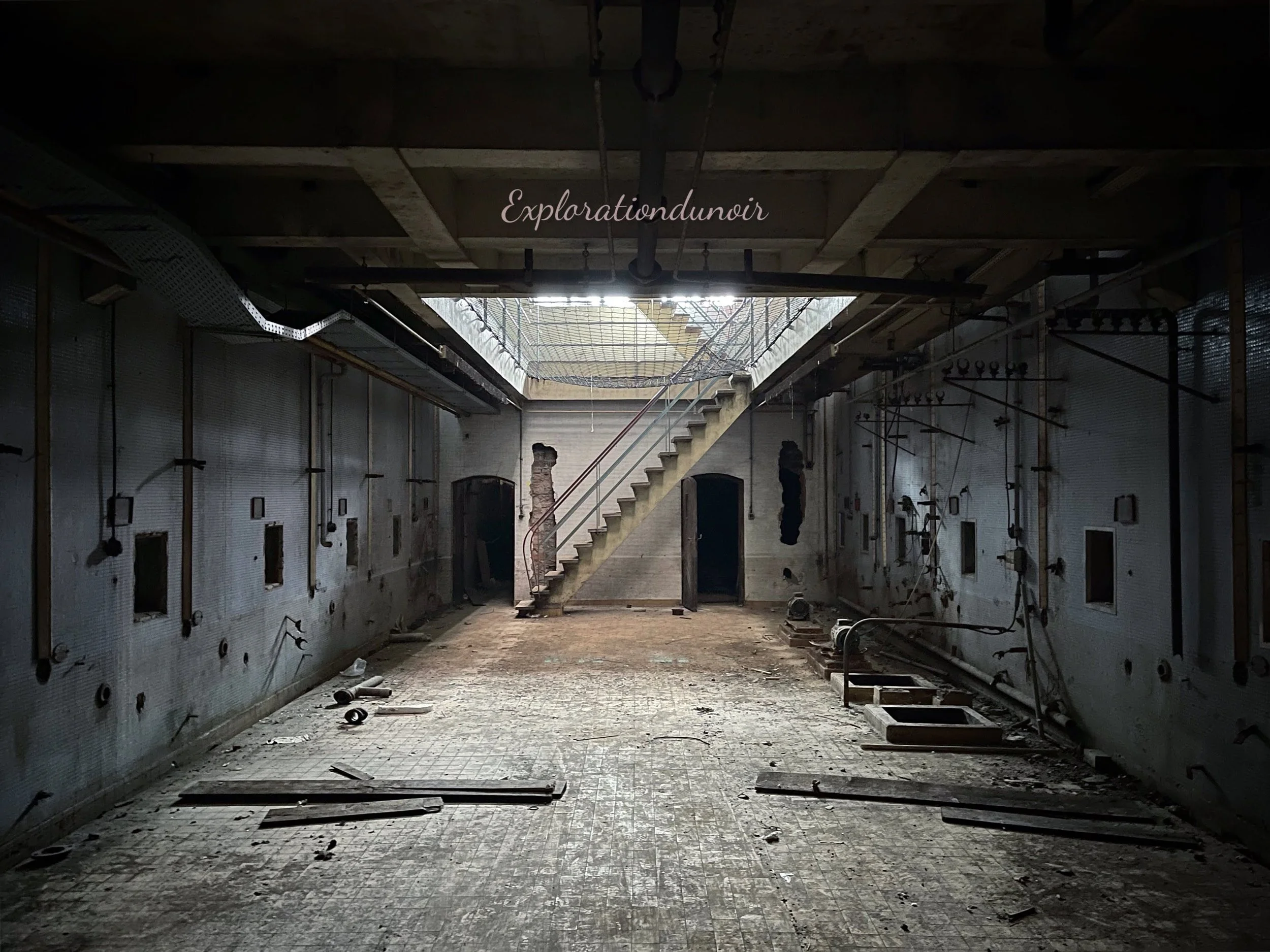 Ancienne usine abandonnée avec murs carrelés et escalier en béton