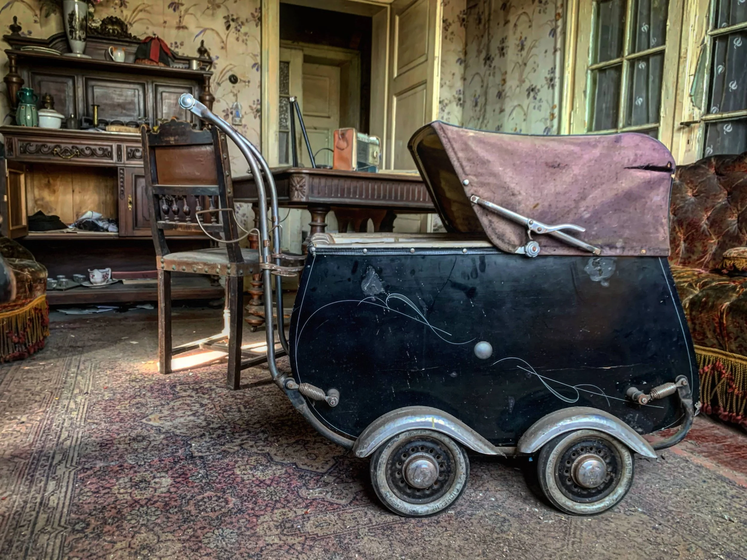 Pièce abandonnée avec meubles anciens et poussette d’enfant