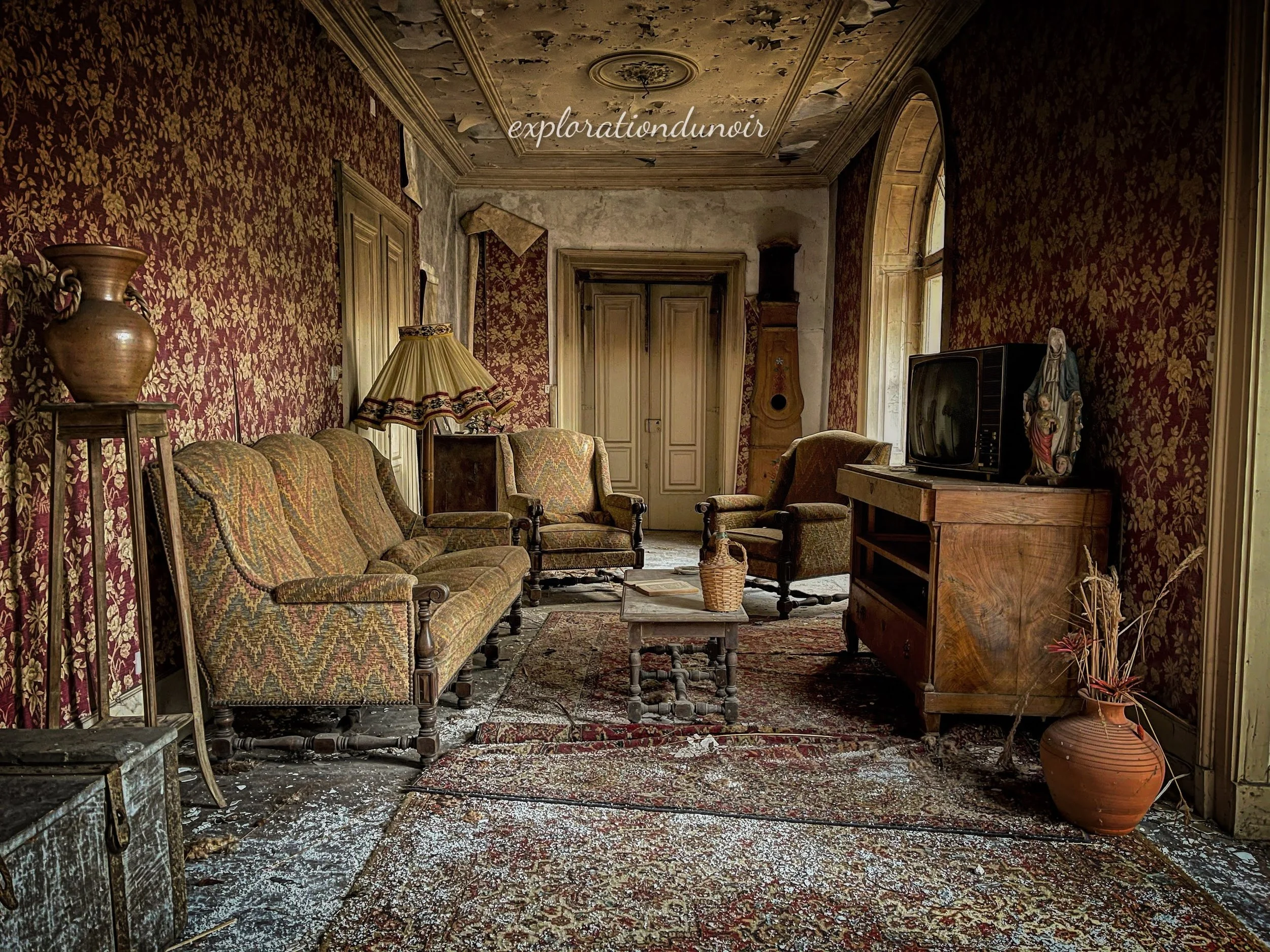 Pièce abandonnée avec papier peint rouge, mobilier ancien et télévision