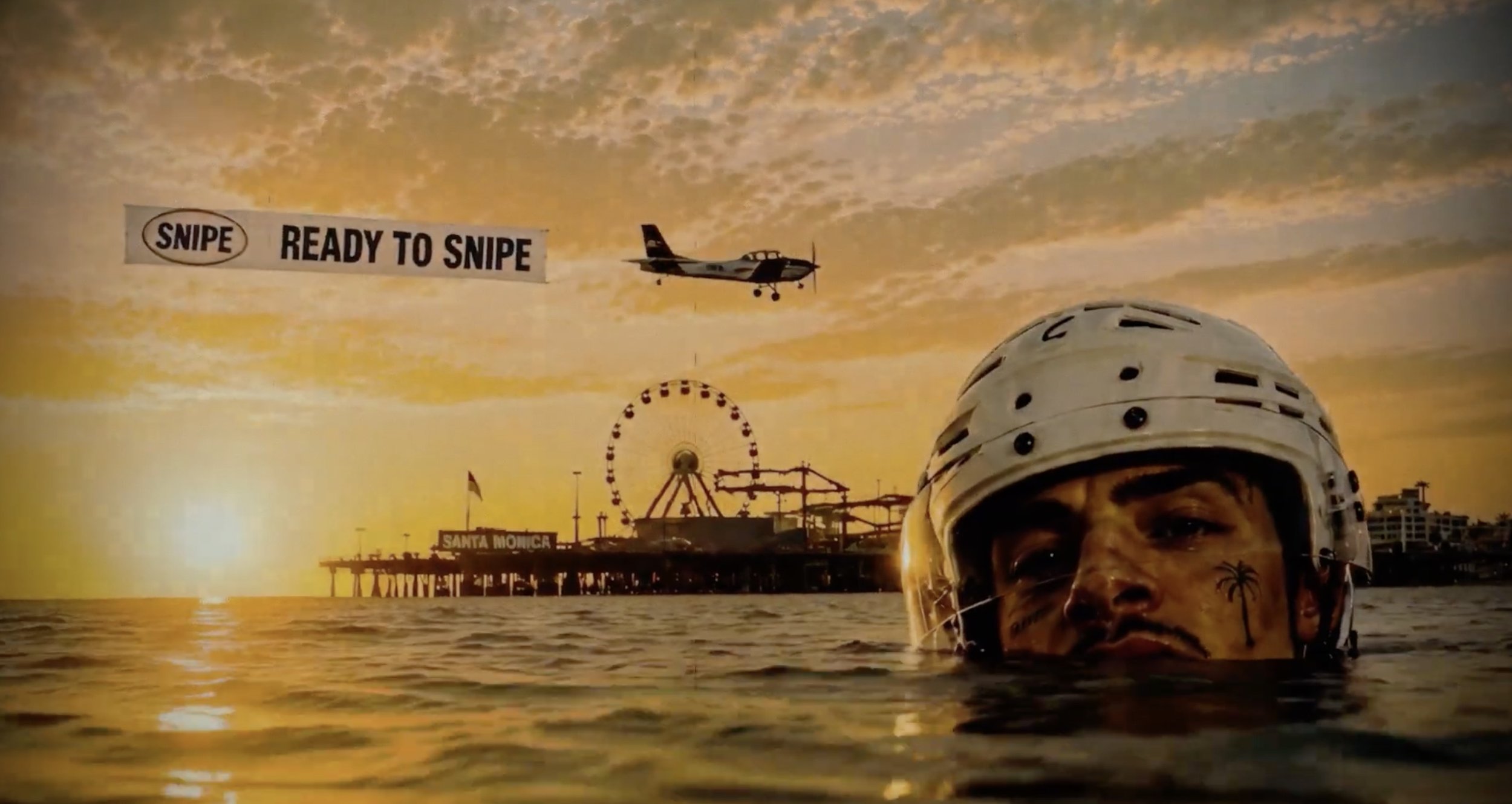 Ciel au coucher du soleil, parc d'attractions Santa Monica, homme portant un casque de moto, signe 'Ready to Snipe' dans le ciel, avion survolant la plage.