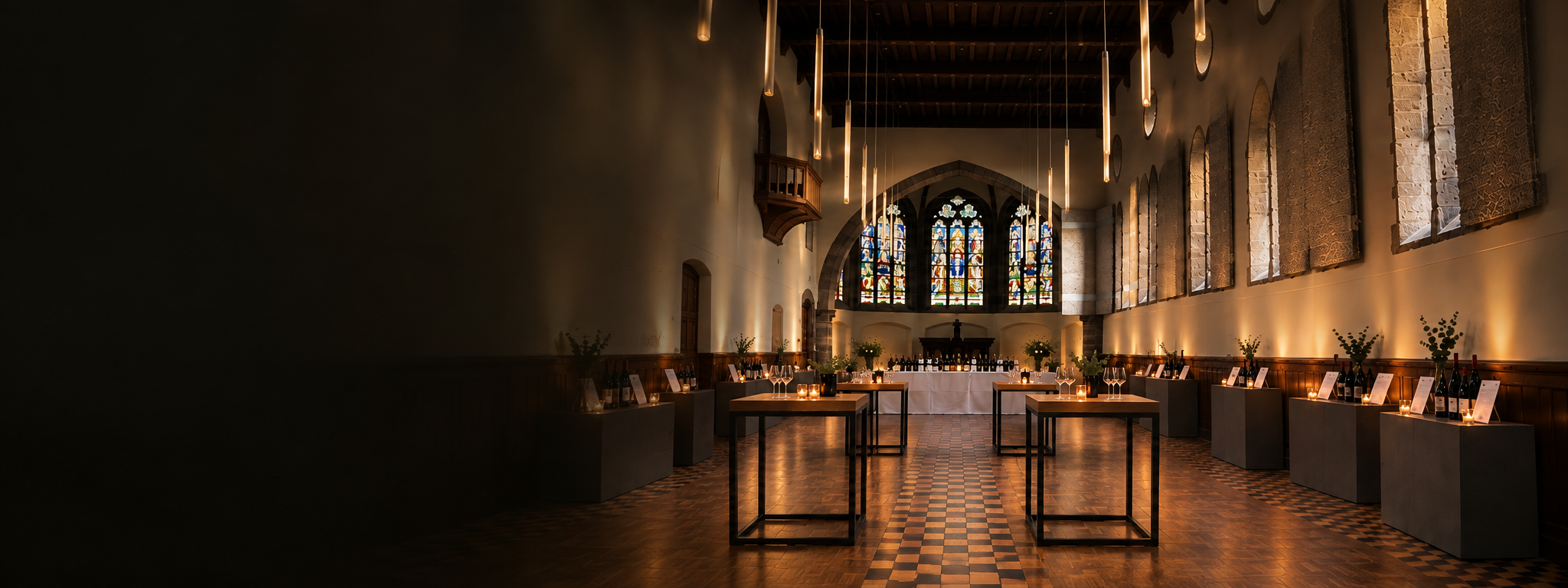Een sfeervolle interieur van een kerk met hoge ramen, decoratie en een gedekte tafel, klaar voor een evenement of een feest.
