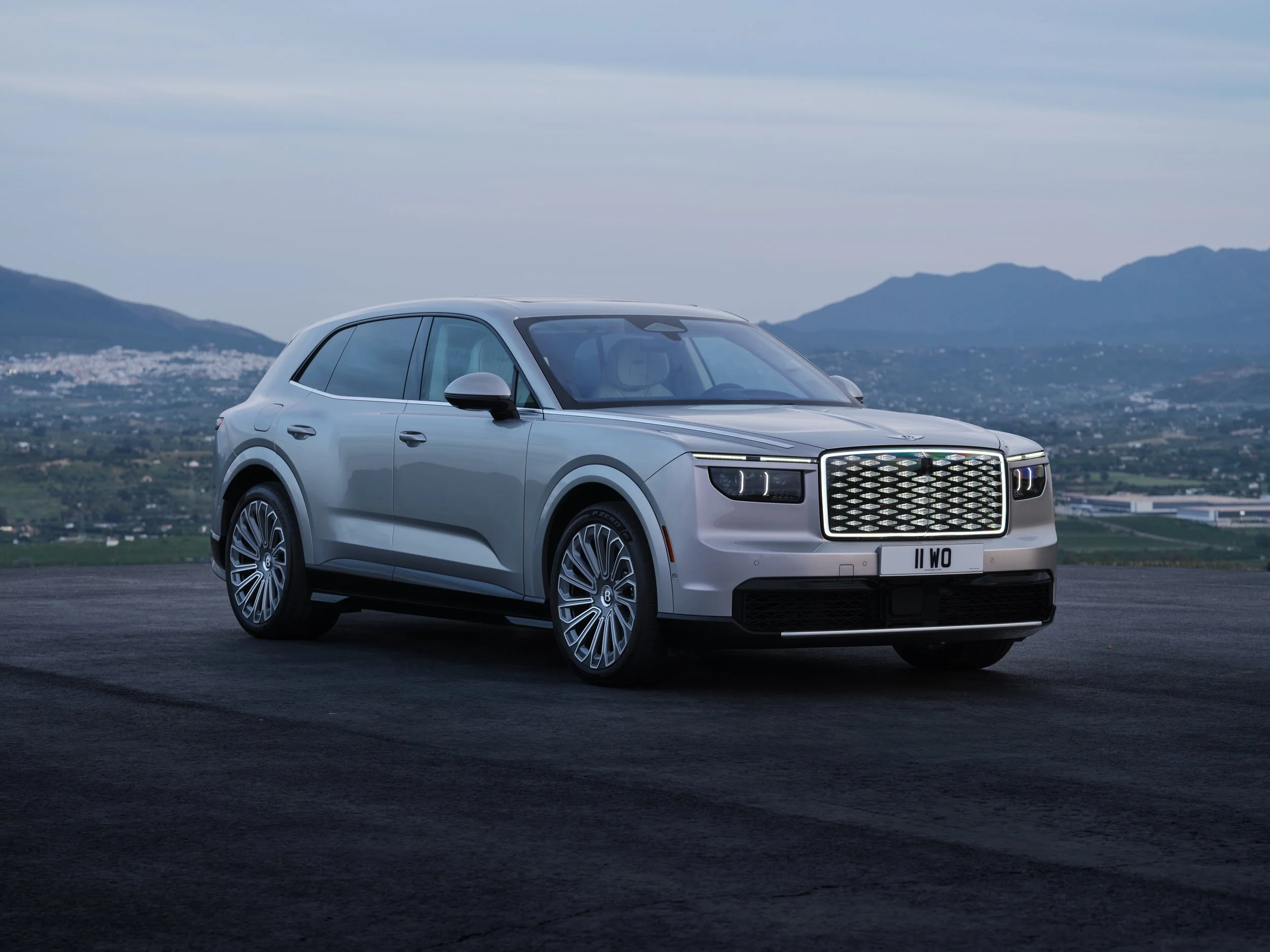Silver Bentley Torcal parked outdoors with mountains in the background.
