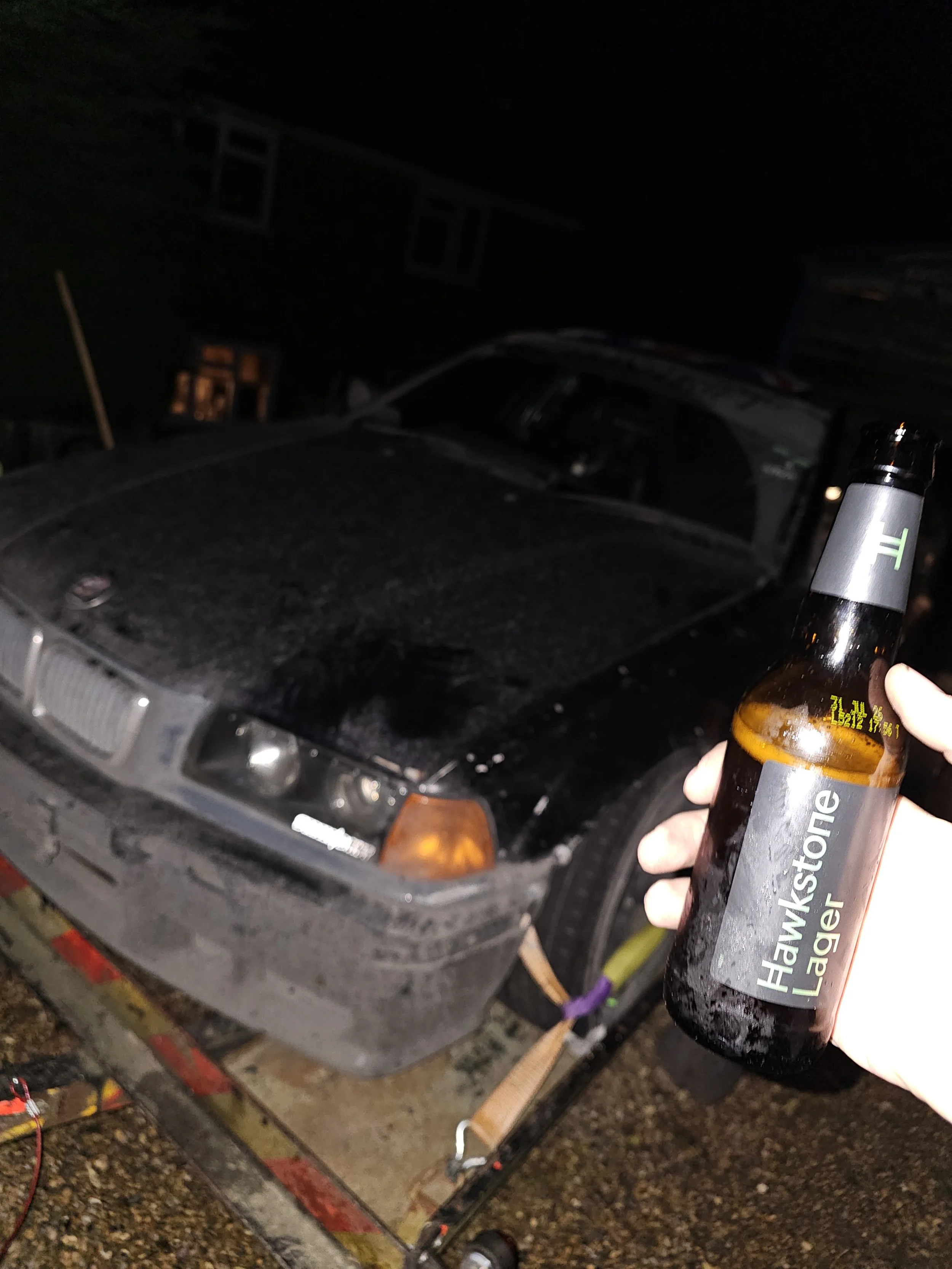 Mechanic holding a bottle of hawk stone after a long night working on the clip point hire drift cars 