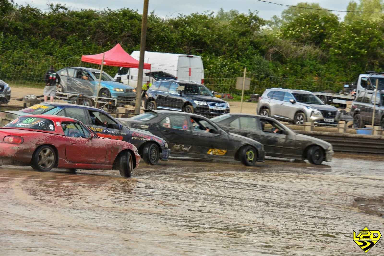 Four drift cars in a slide on track during a drift day being watched by spectators.