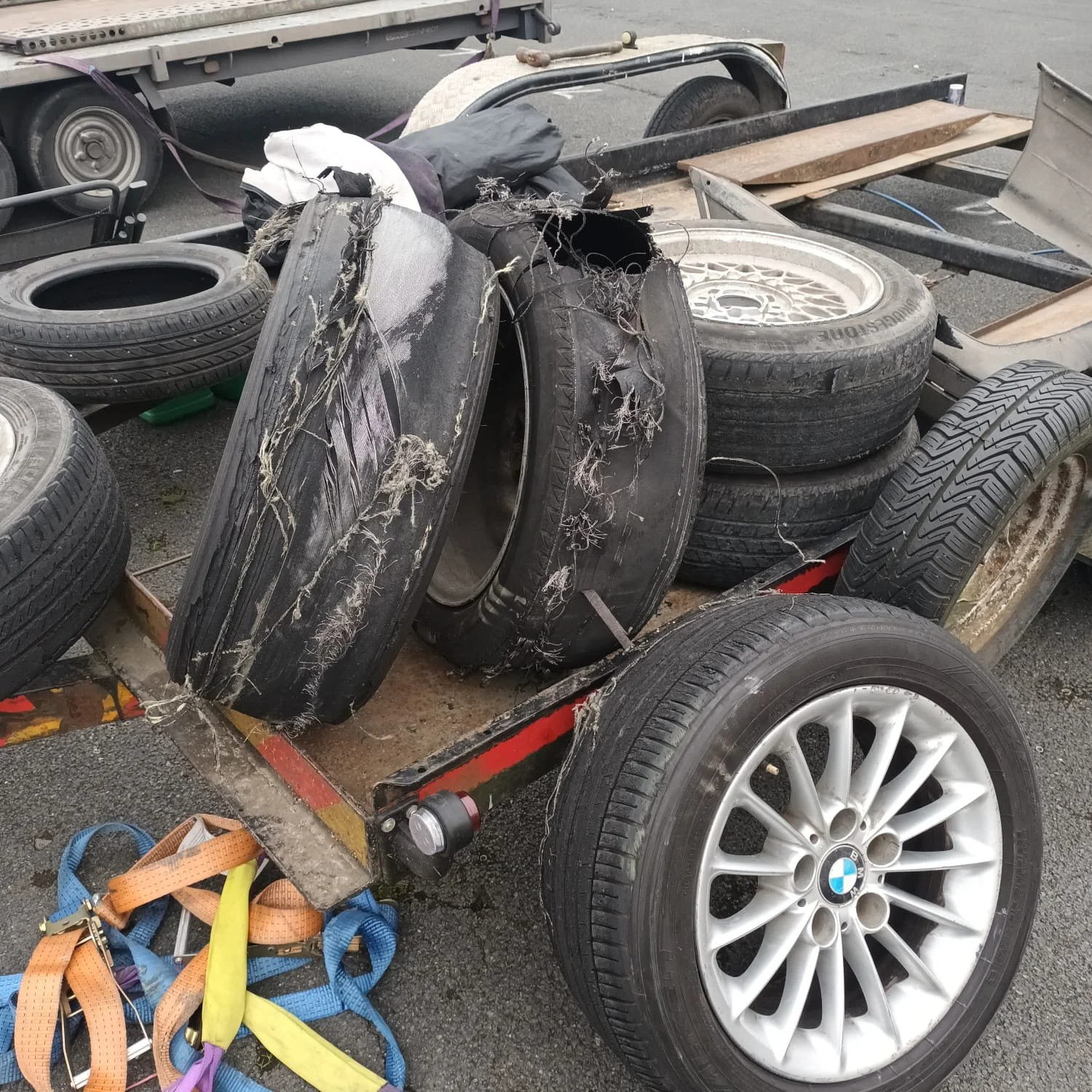 Stack of shredded tyres on a flatbed trailer, with some wrecked tire rims after a good day drifting