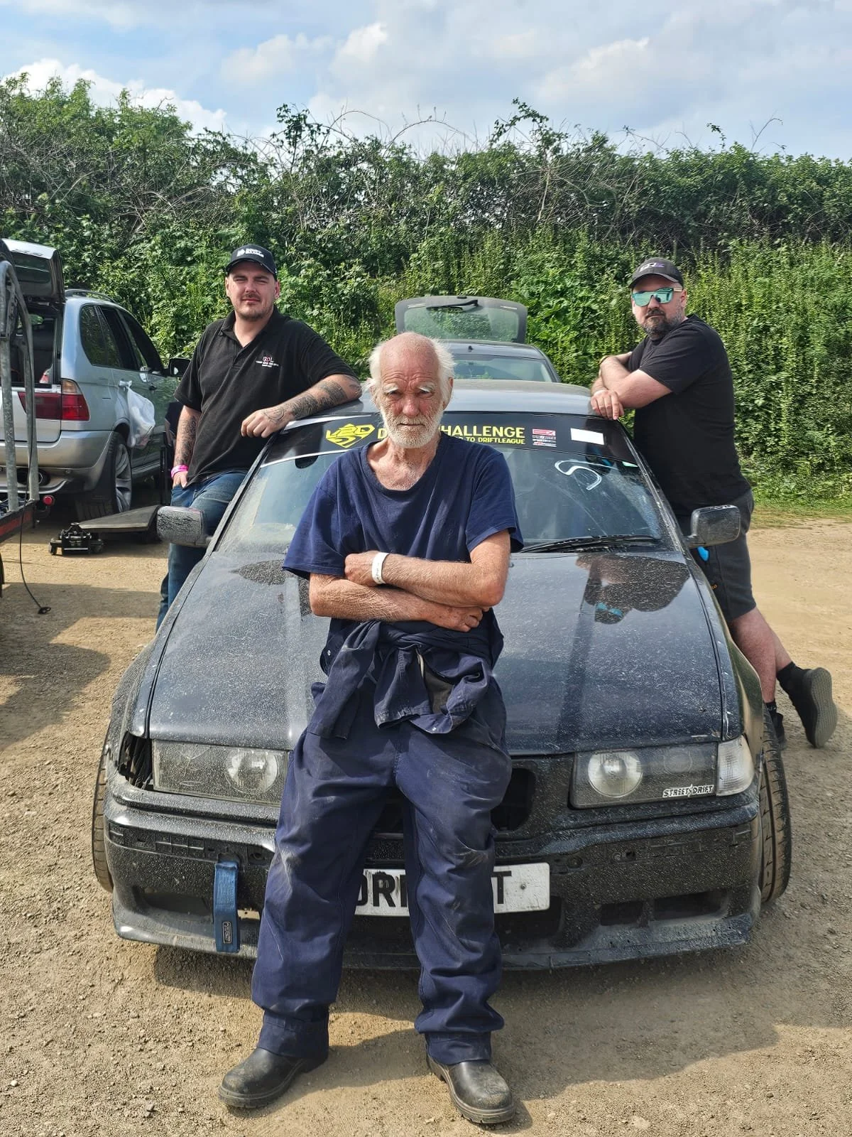 The boss of clip point hire leaning on his e36 drift car, posing for a photo with his dad and brother.