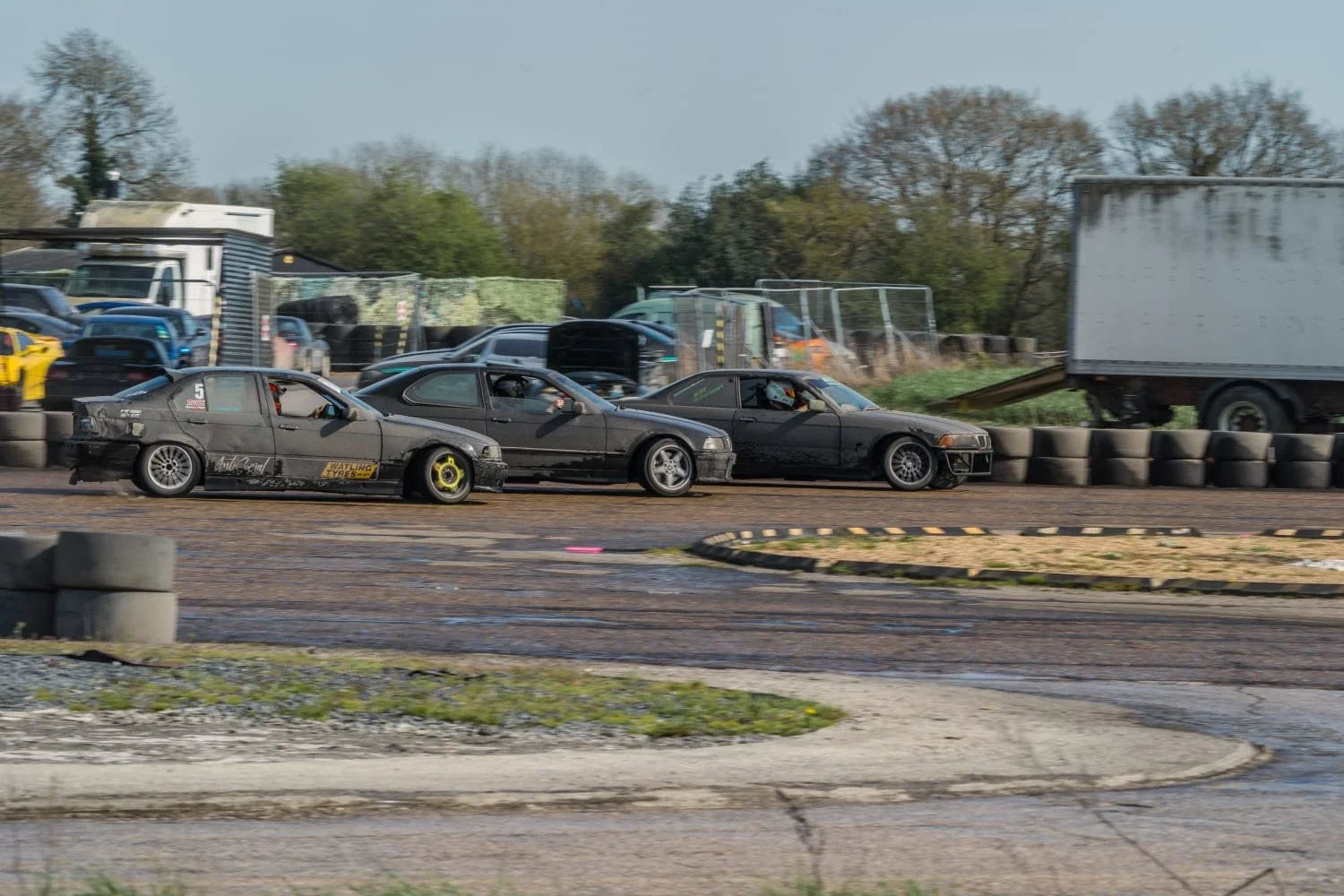 Three drift cars sliding round a drift track