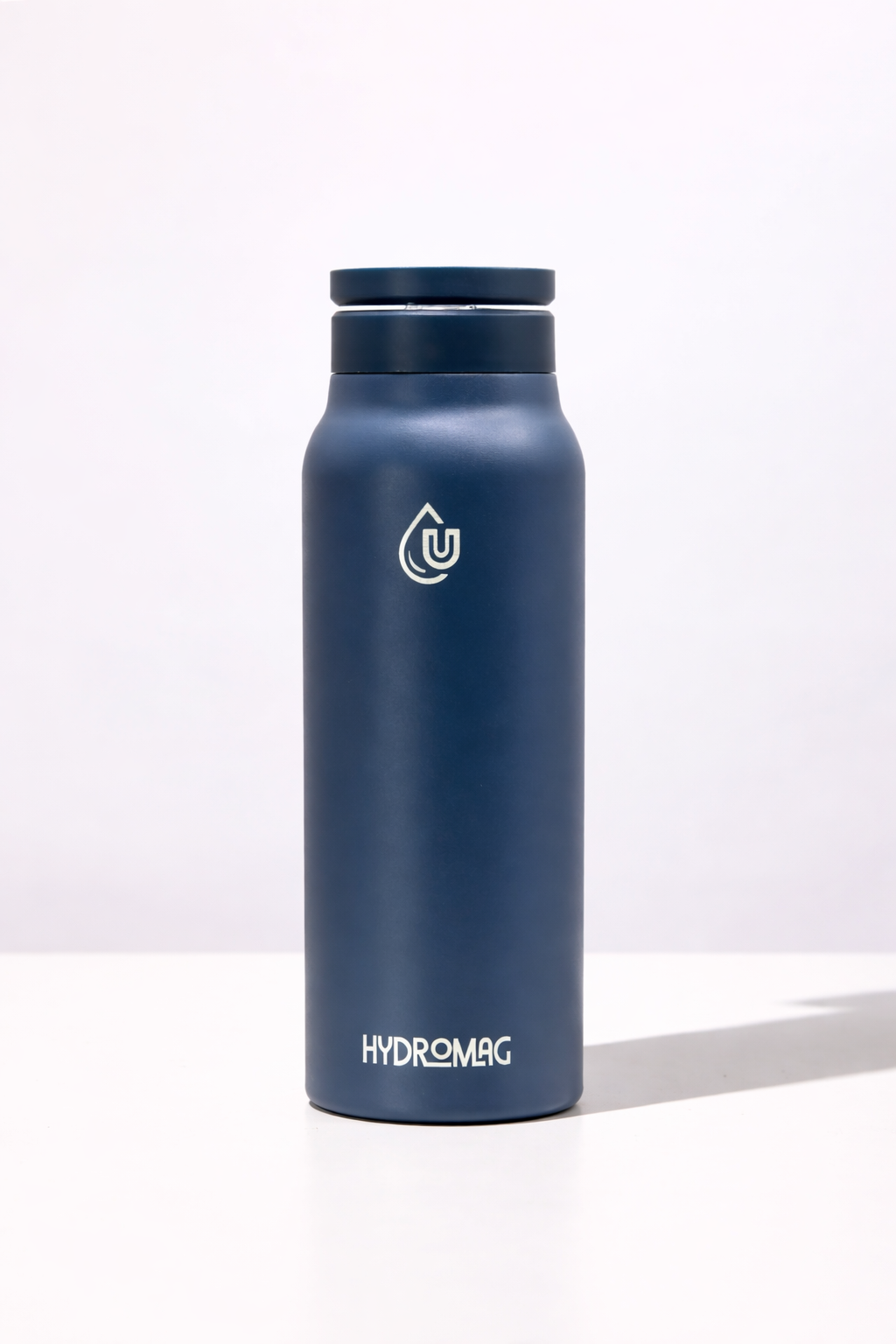 A navy blue Hydromag water bottle standing on a white surface against a white background.