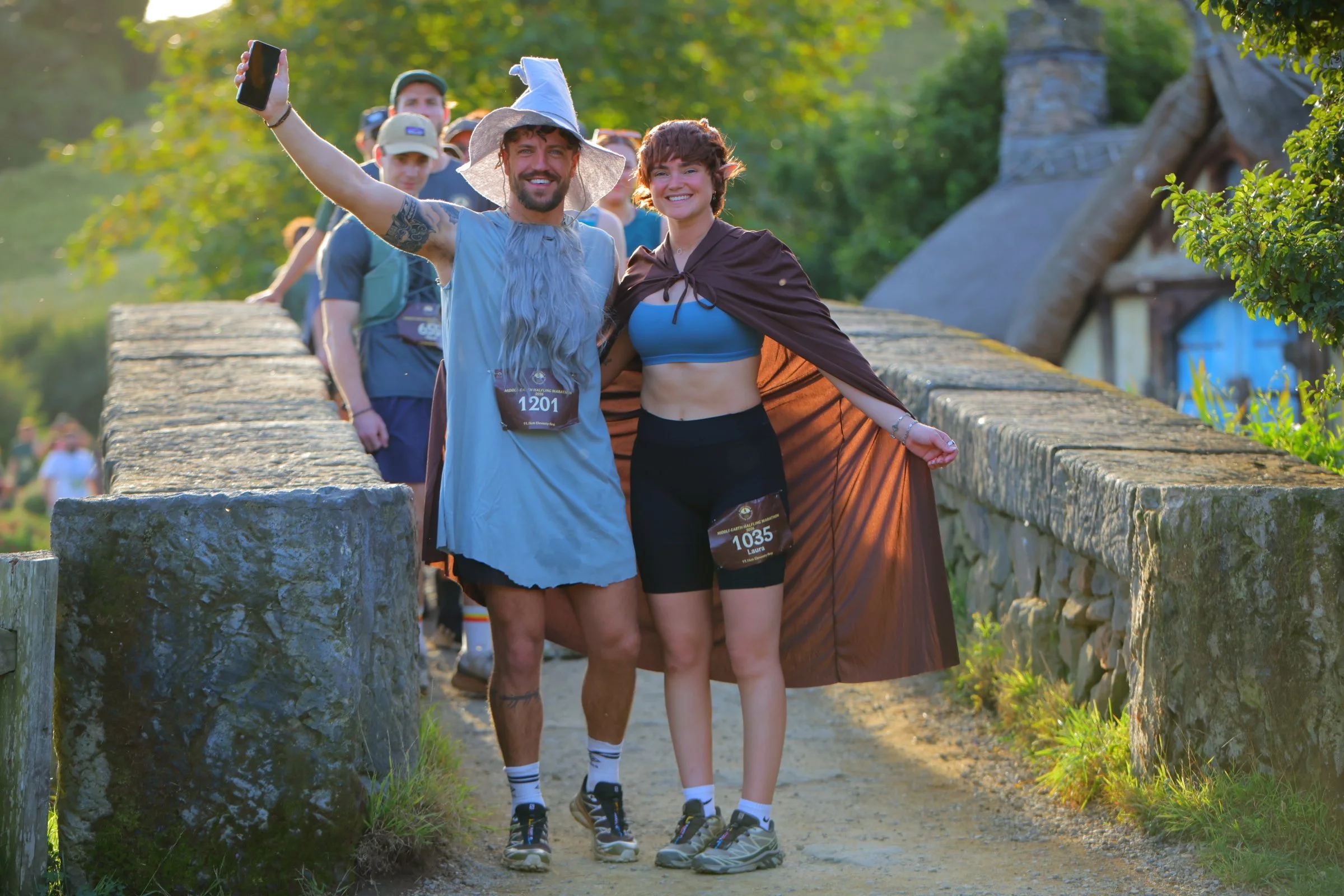 A group of people participating in a marathon, taking a selfie on a bridge in a park with green trees in the background.