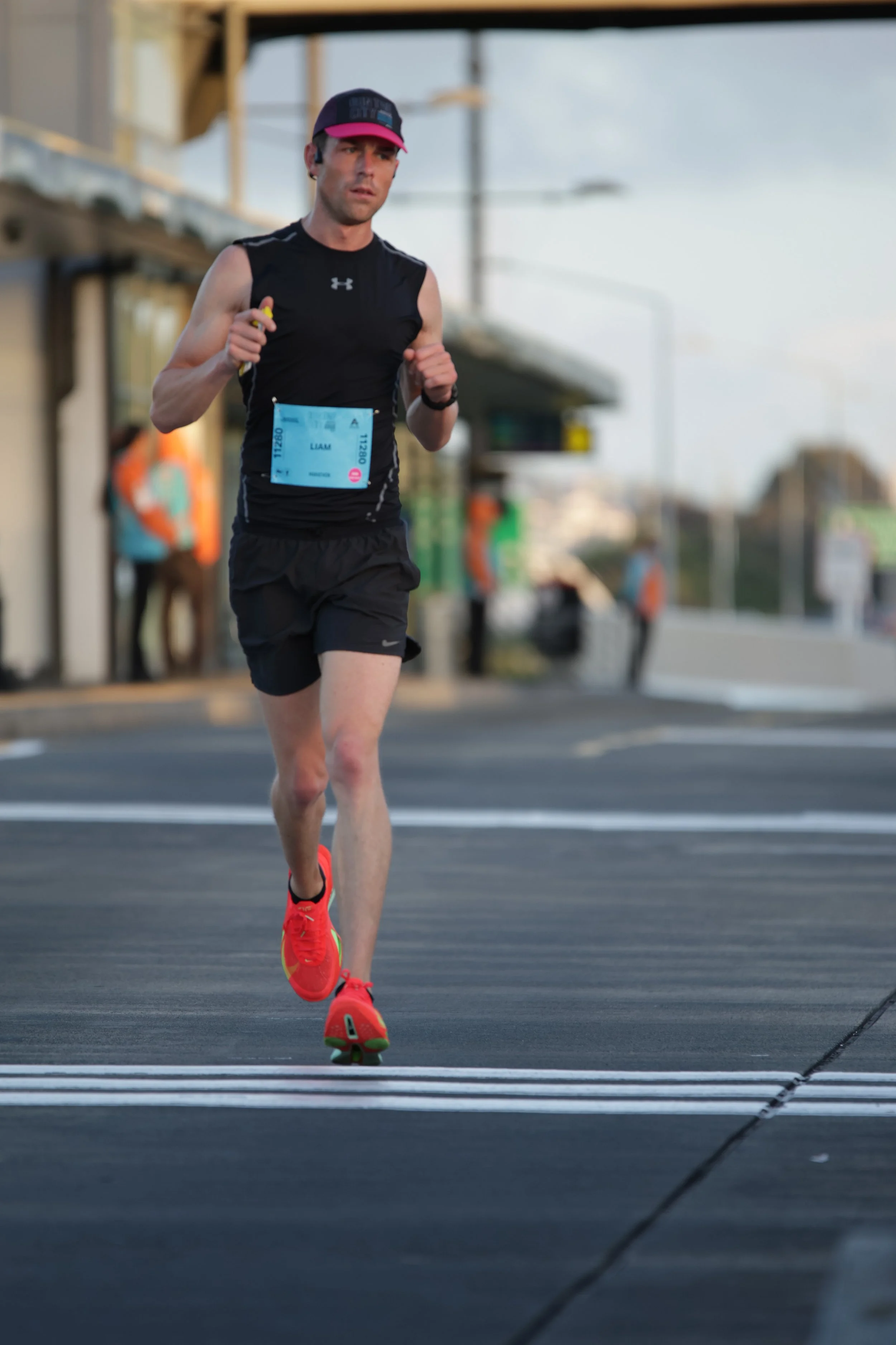 A male runner with a race bib running on a street during daytime.