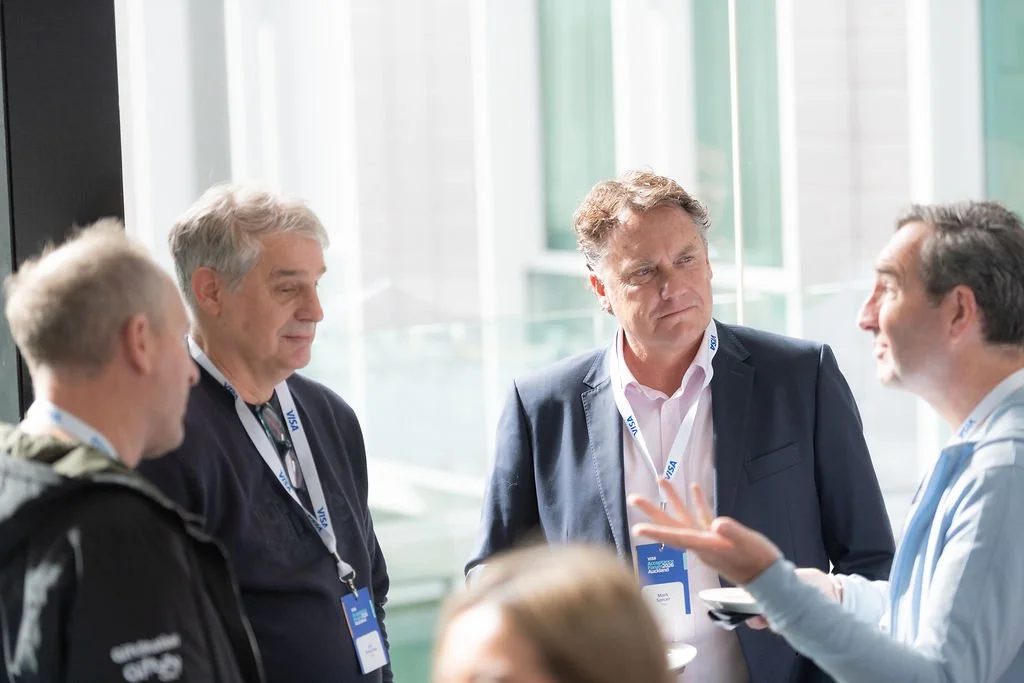 Group of professional men in business attire conversing at a conference.
