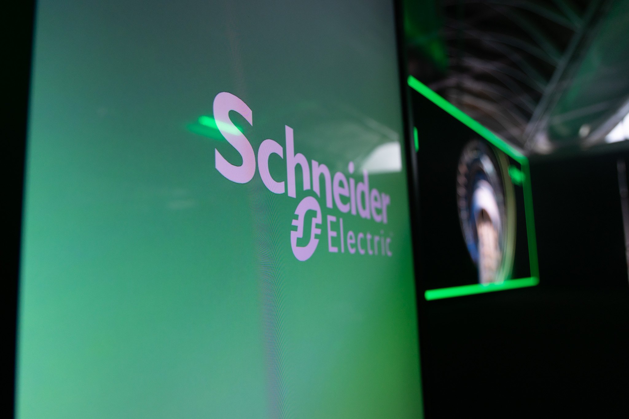 Close-up of a digital screen displaying a logo and text for Schneider Electric, with green lighting accents.