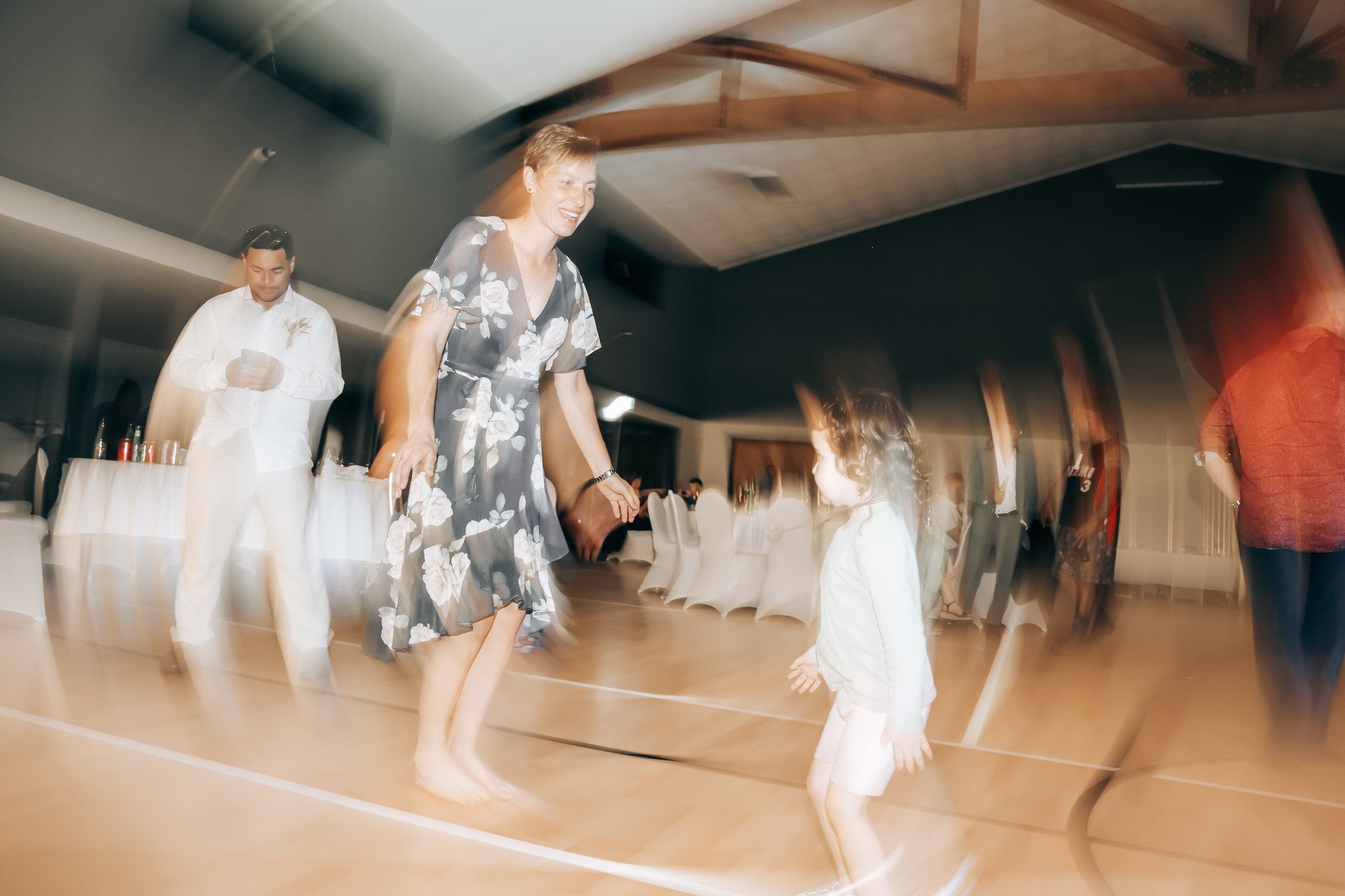 A woman dancing with a young girl at a party or celebration in a decorated indoor venue.