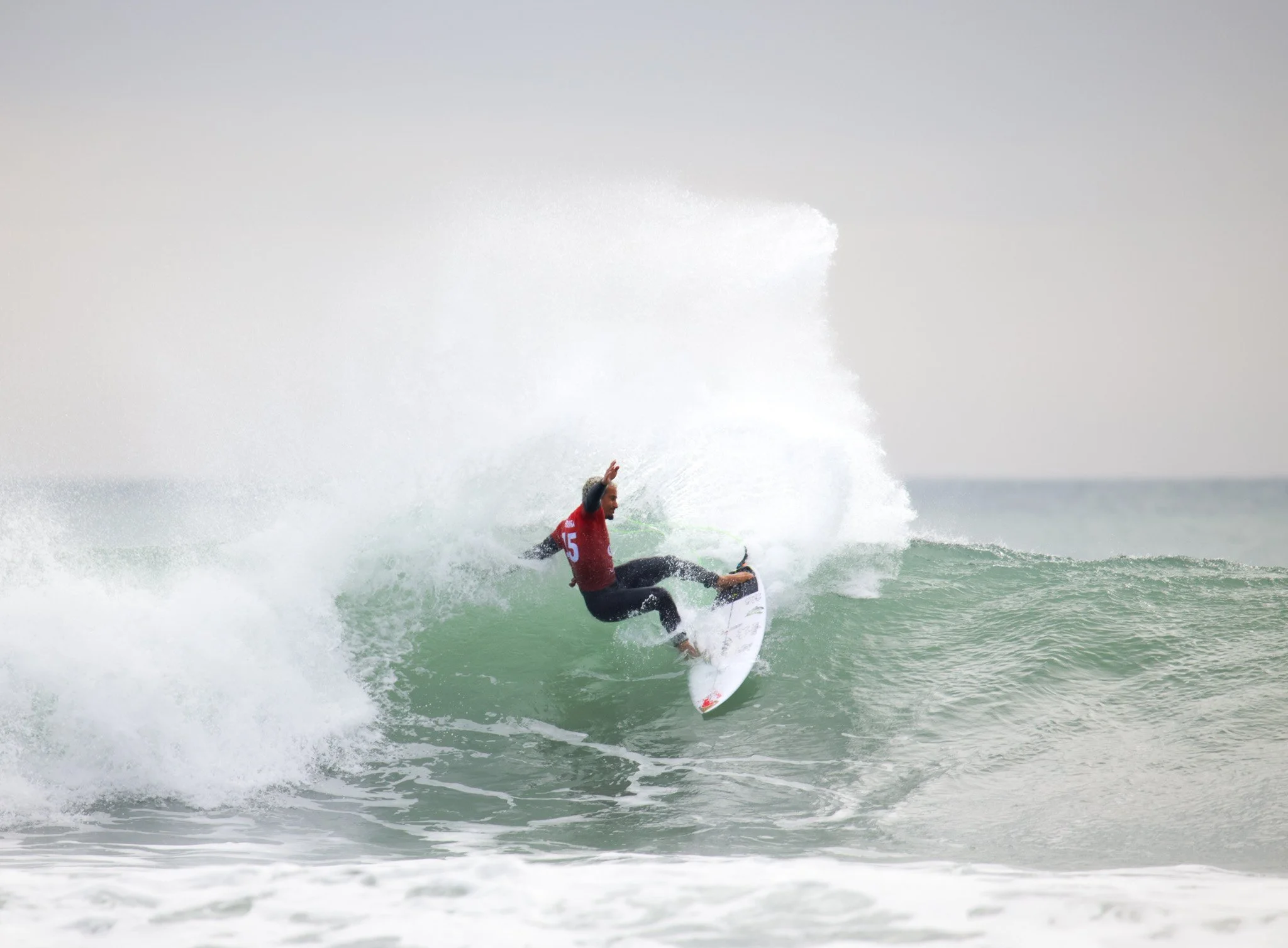 A surfer riding a wave in the ocean on a cloudy day.