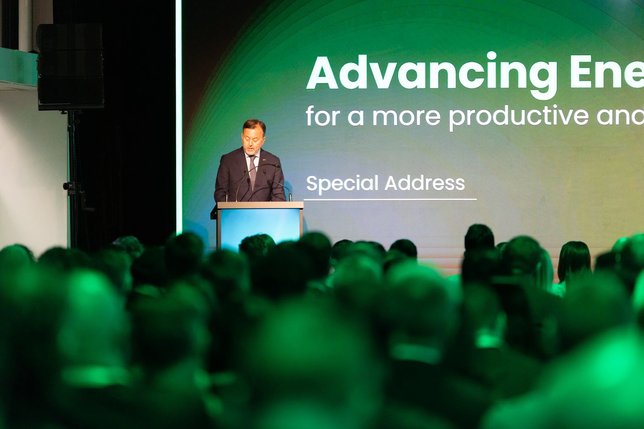 A man in a suit giving a speech at a conference with a large screen that reads 'Advancing Energy for a more productive and sustainable future' and 'Special Address'. The conference is attended by a large audience.