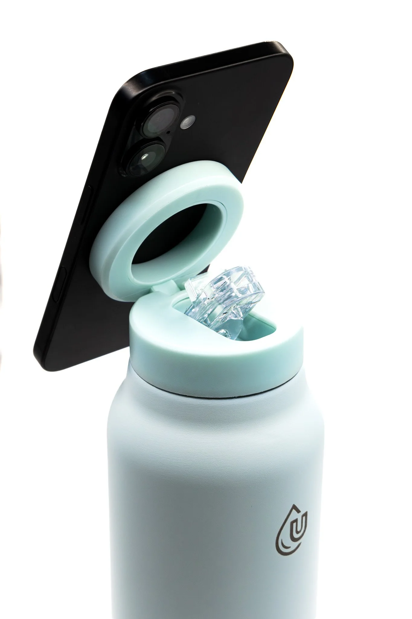 Smartphone mounted on a white liquid soap dispenser with a transparent spout and a black camera lens.