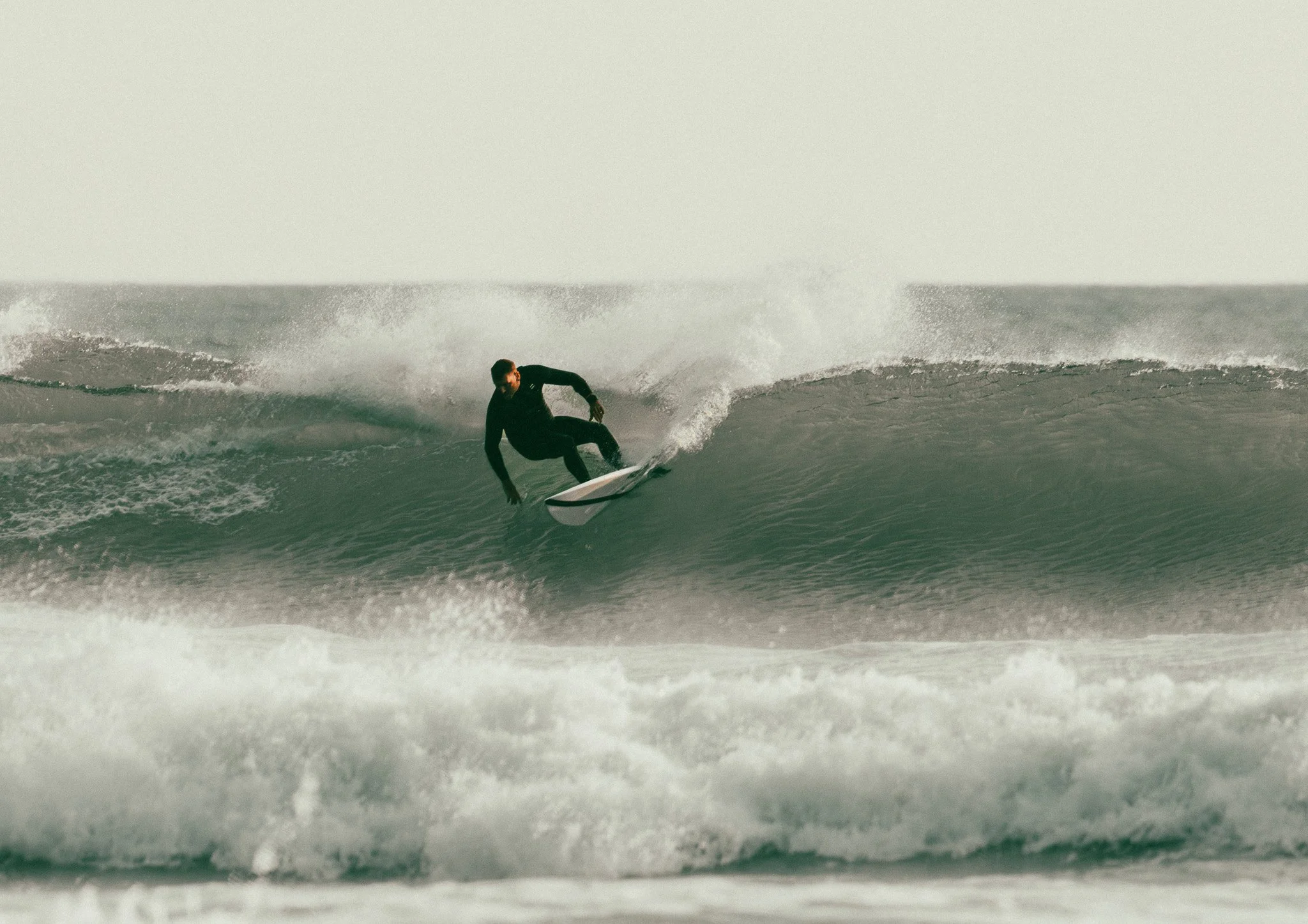 A person in a wetsuit surfing on a wave in the ocean.