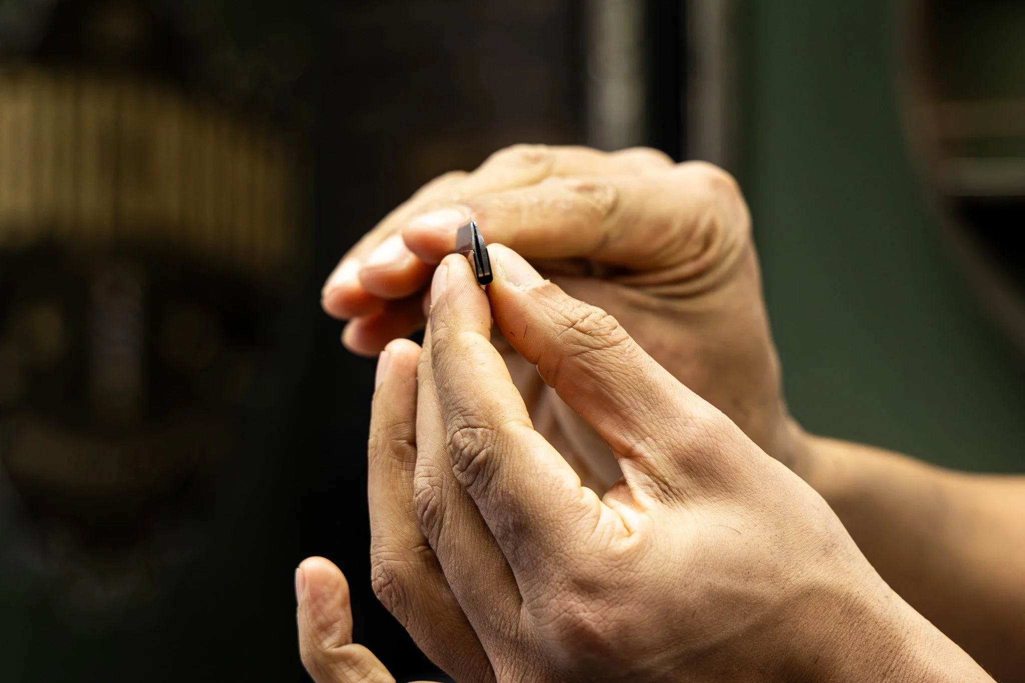 Hands holding a small razor blade.