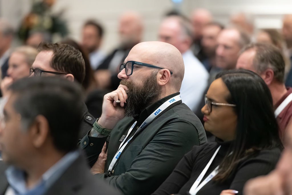A group of people attending a conference or seminar, sitting and listening attentively.