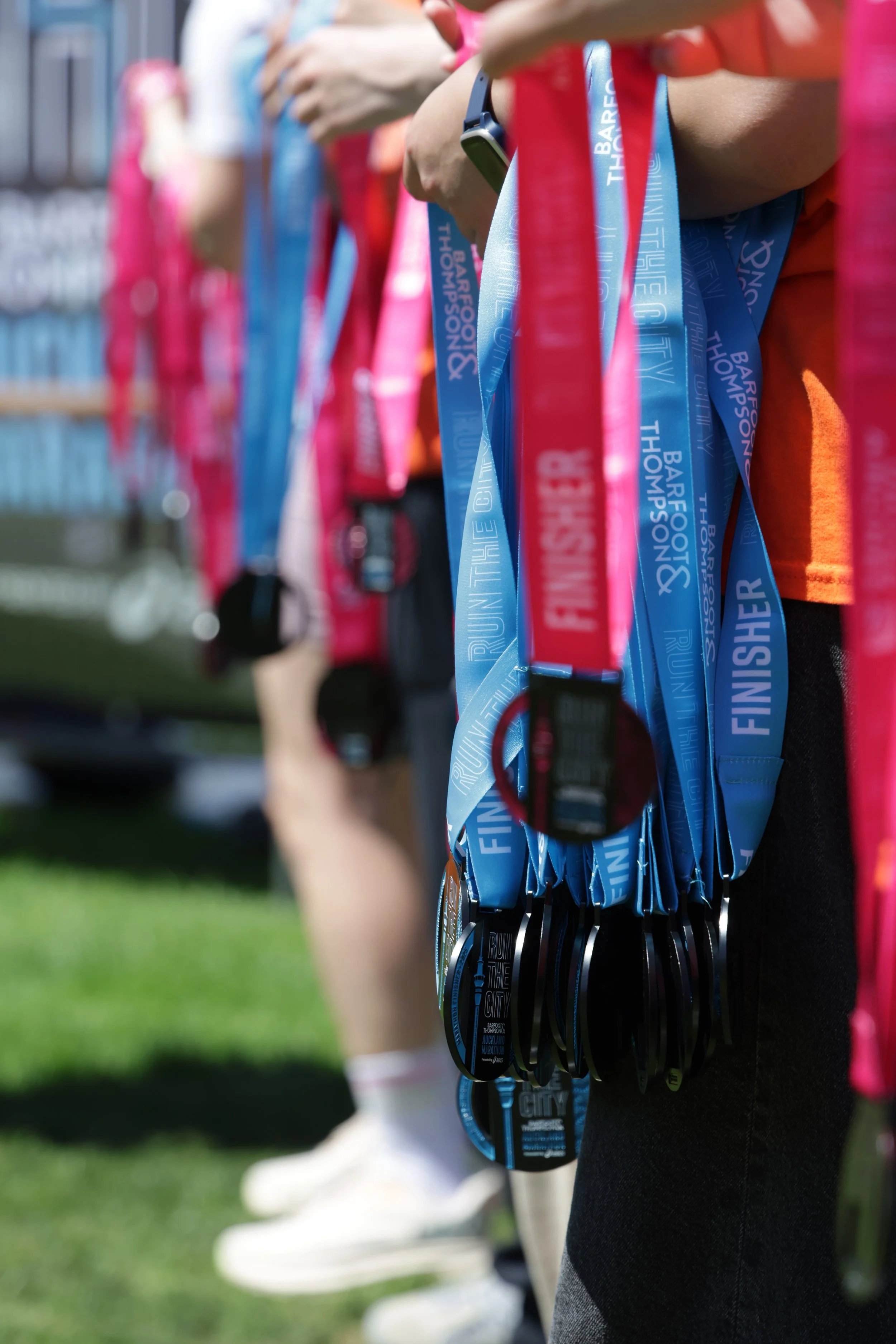 Close-up of a row of medals hanging from lanyards, received at the Barfoot & Thorped Rune the City event, with participants standing in line.