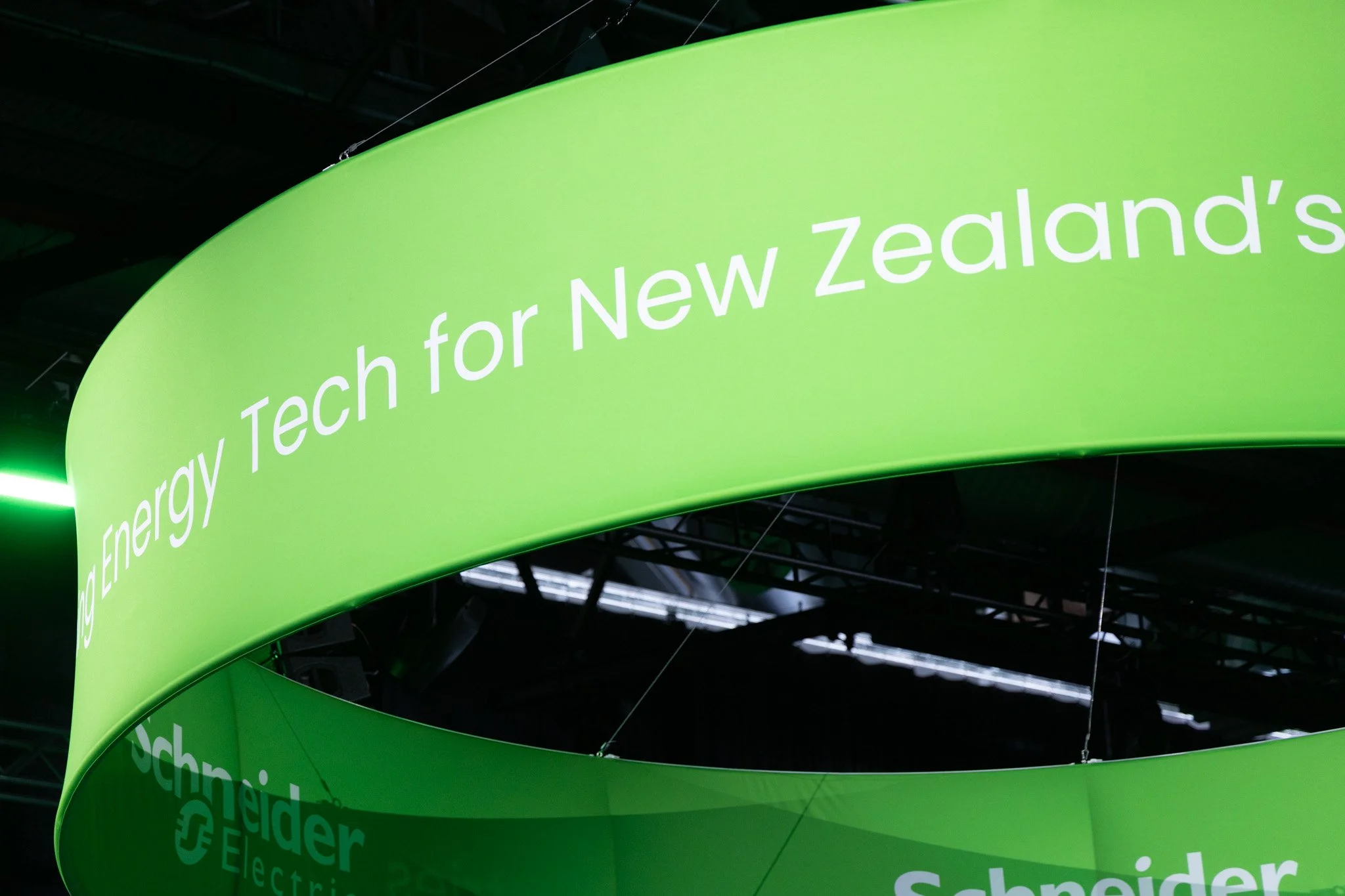 Bright green curved banner with white text that reads 'Energy/Technology for New Zealand' displayed at an indoor event or exhibition.