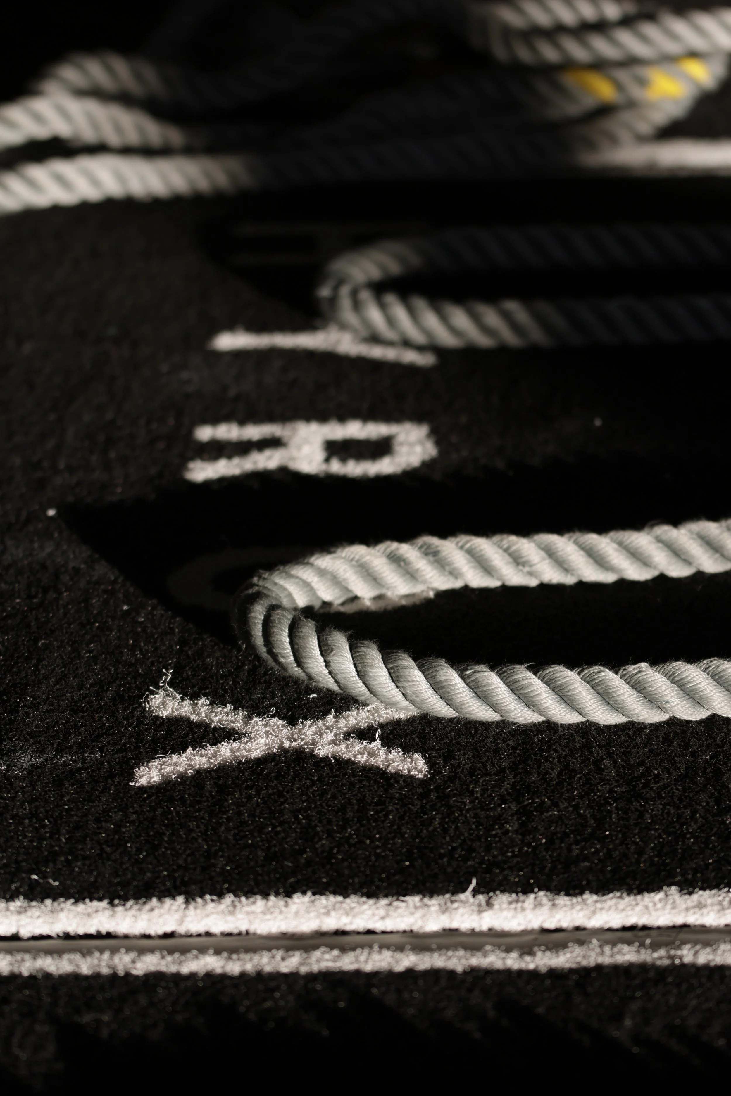 Close-up of several white and black climbing ropes on a dark surface with white chalk marks.