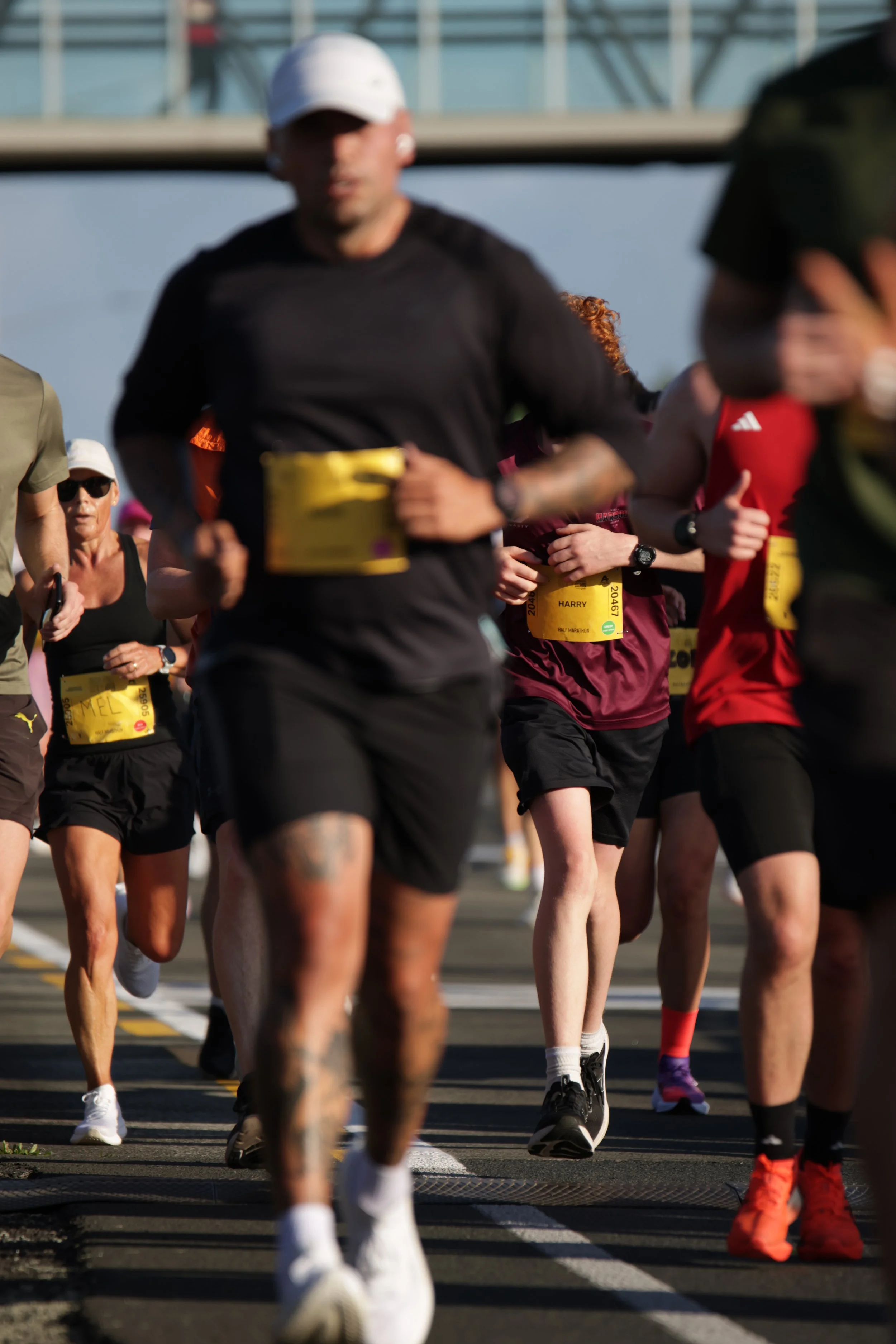 Multiple people running in a marathon race outdoors, wearing athletic clothing and bib numbers.