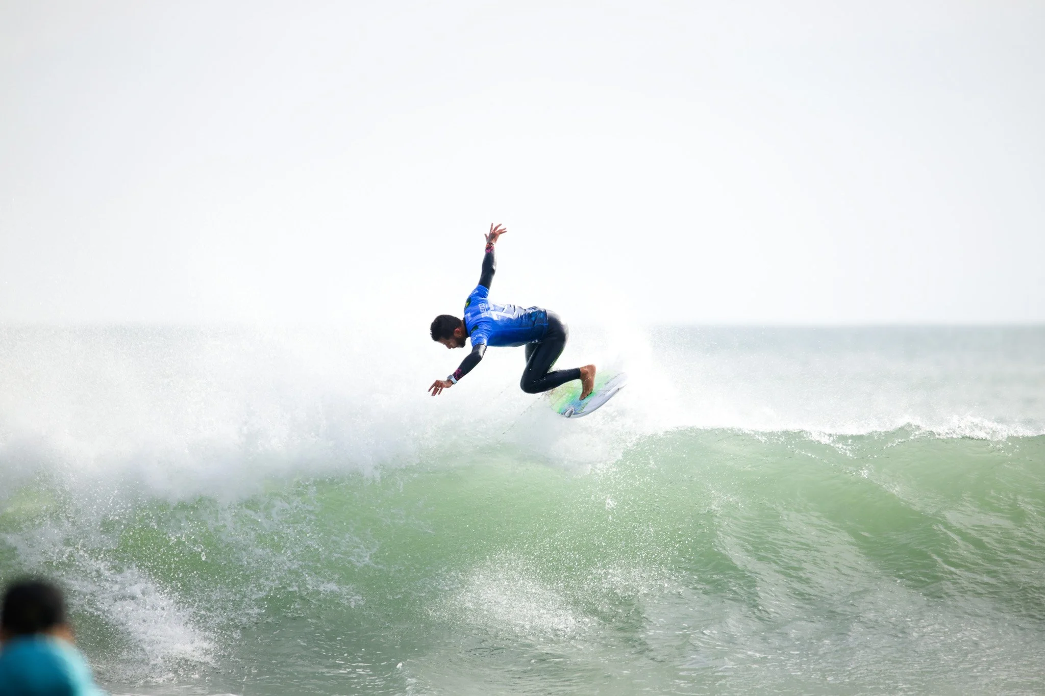 Surfer in blue wetsuit riding a wave on a surfing board in the ocean.