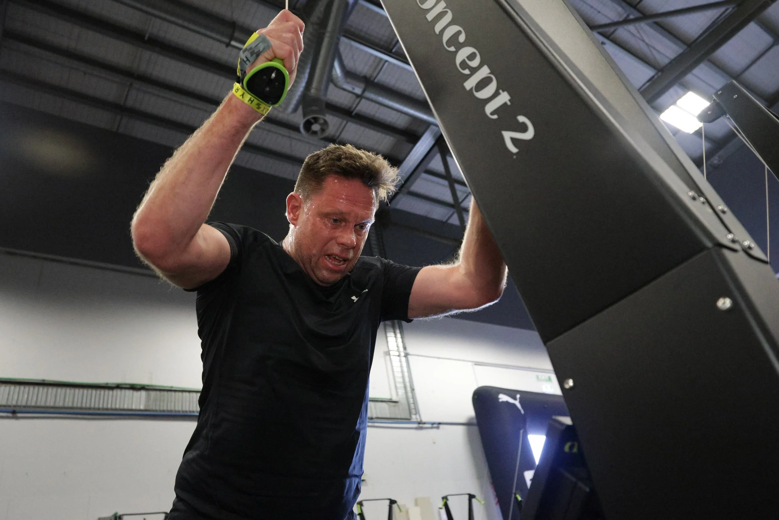 A man working out at a gym, holding onto a piece of fitness equipment, with a focused expression.