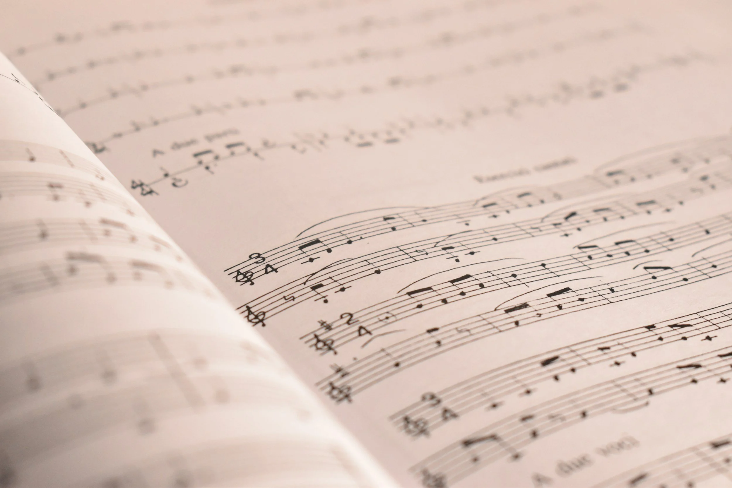 Nært bilde av åpnet noteskriving med musikalske notater og symboler på en side.