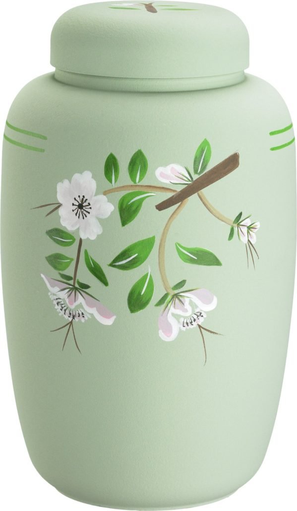 En lys grønn urne med blomster- og grenerykDesign, dekorert med hvite blomster og grønne blader.