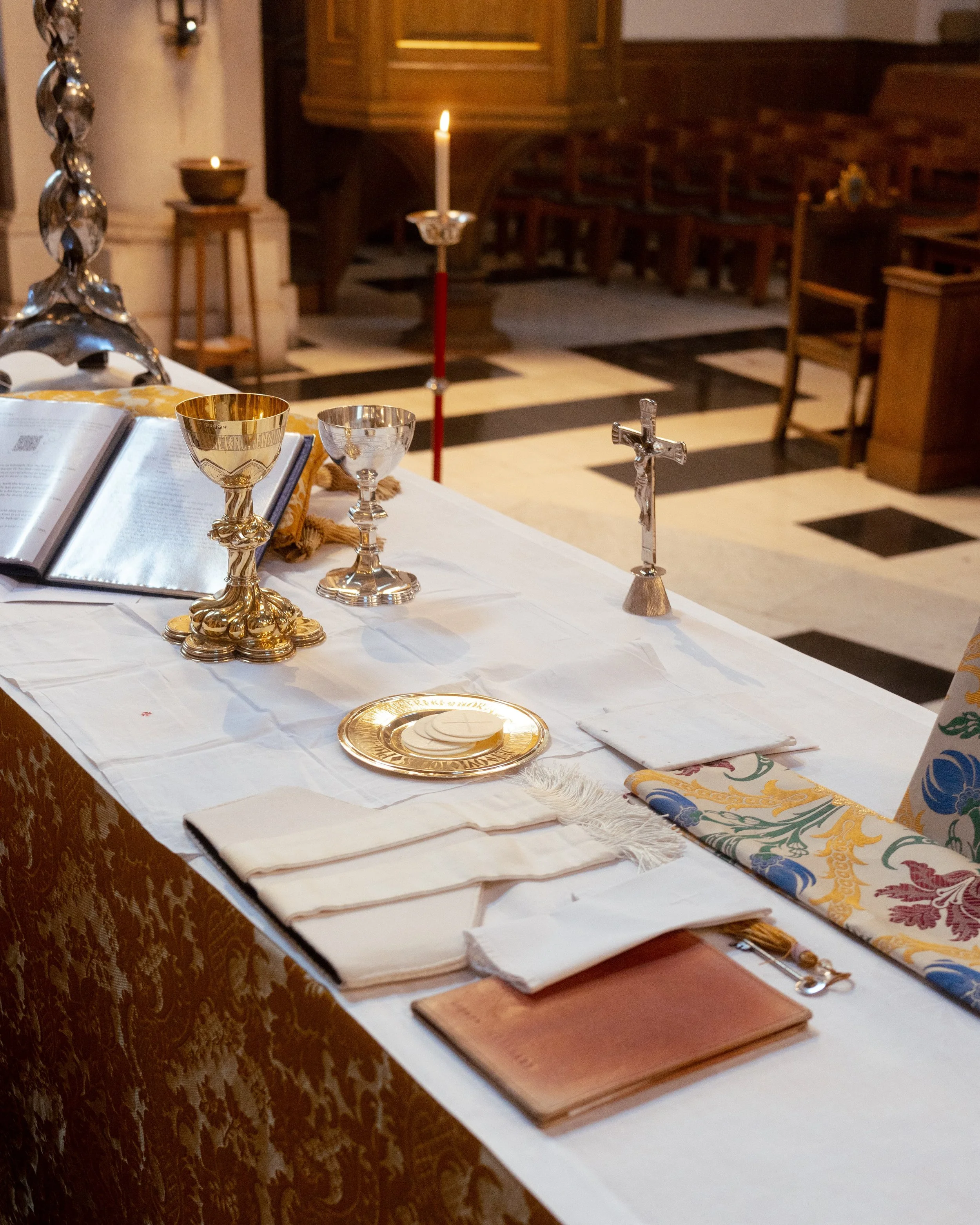 Altar table with religious items including a Bible, chalice, and candles inside a church.