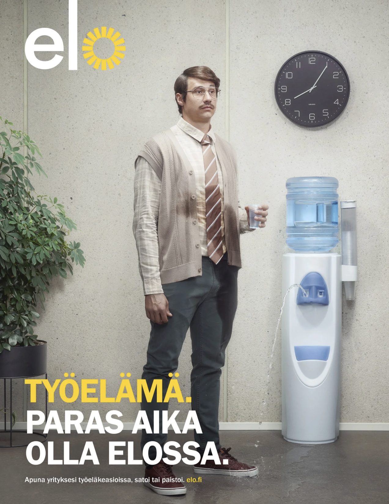 A man standing next to a water cooler in an office, holding a glass of water. Ad photography production.