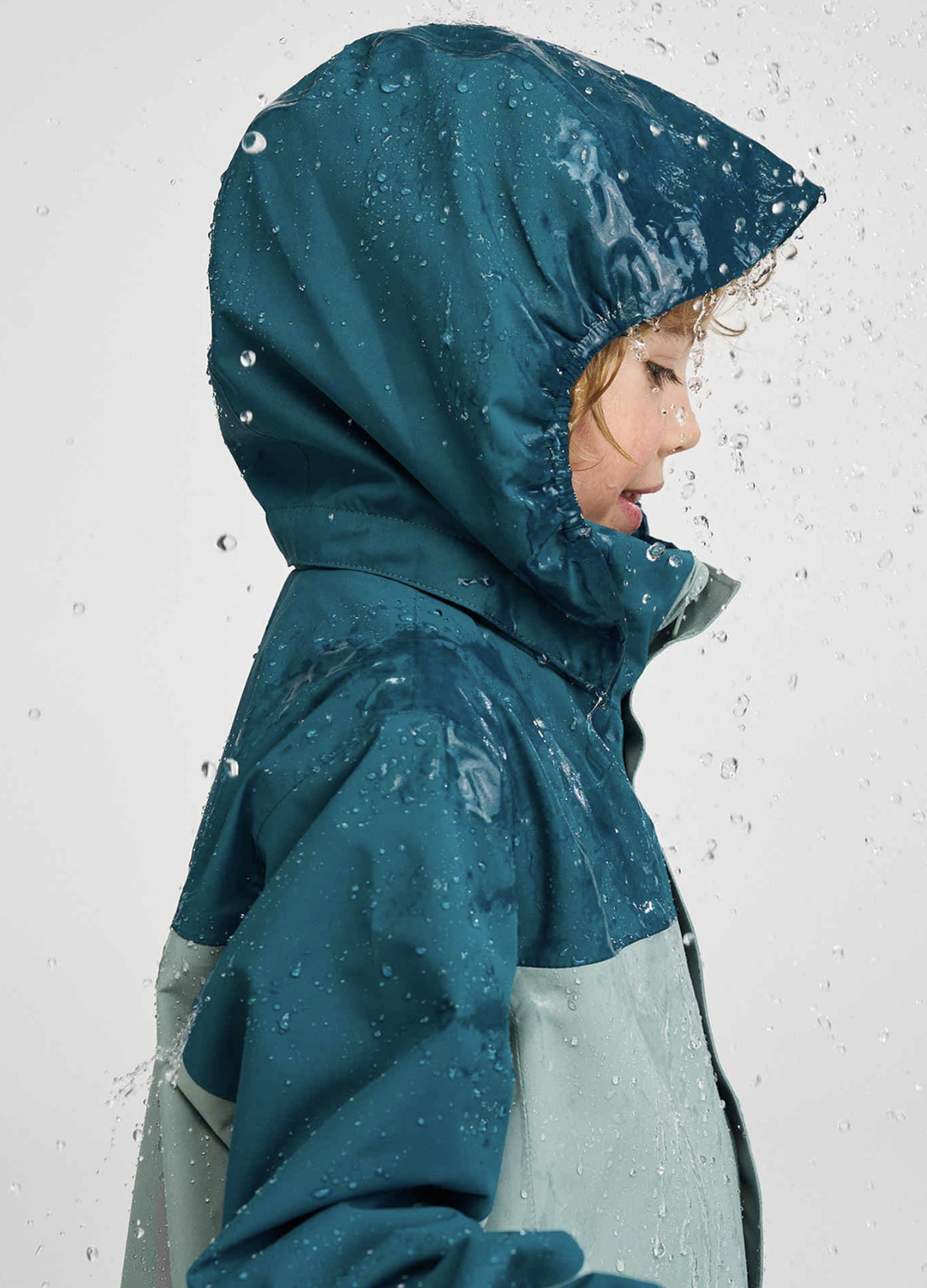 Side profile of a child in a rain jacket. Studio photo with rain, Ad photo for Reima.