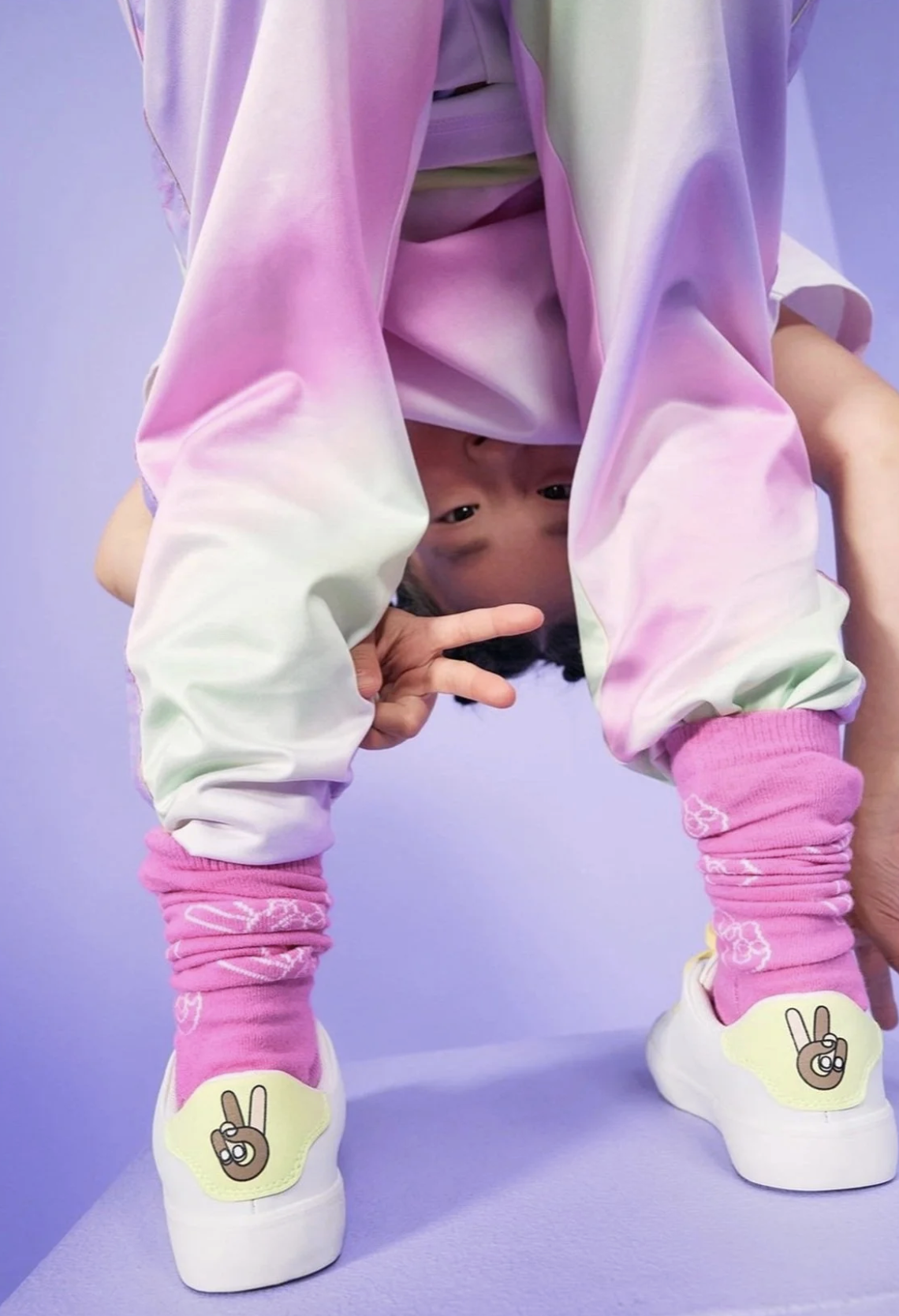 Child in colorful outfit against a purple background. Ad photo for Reima.