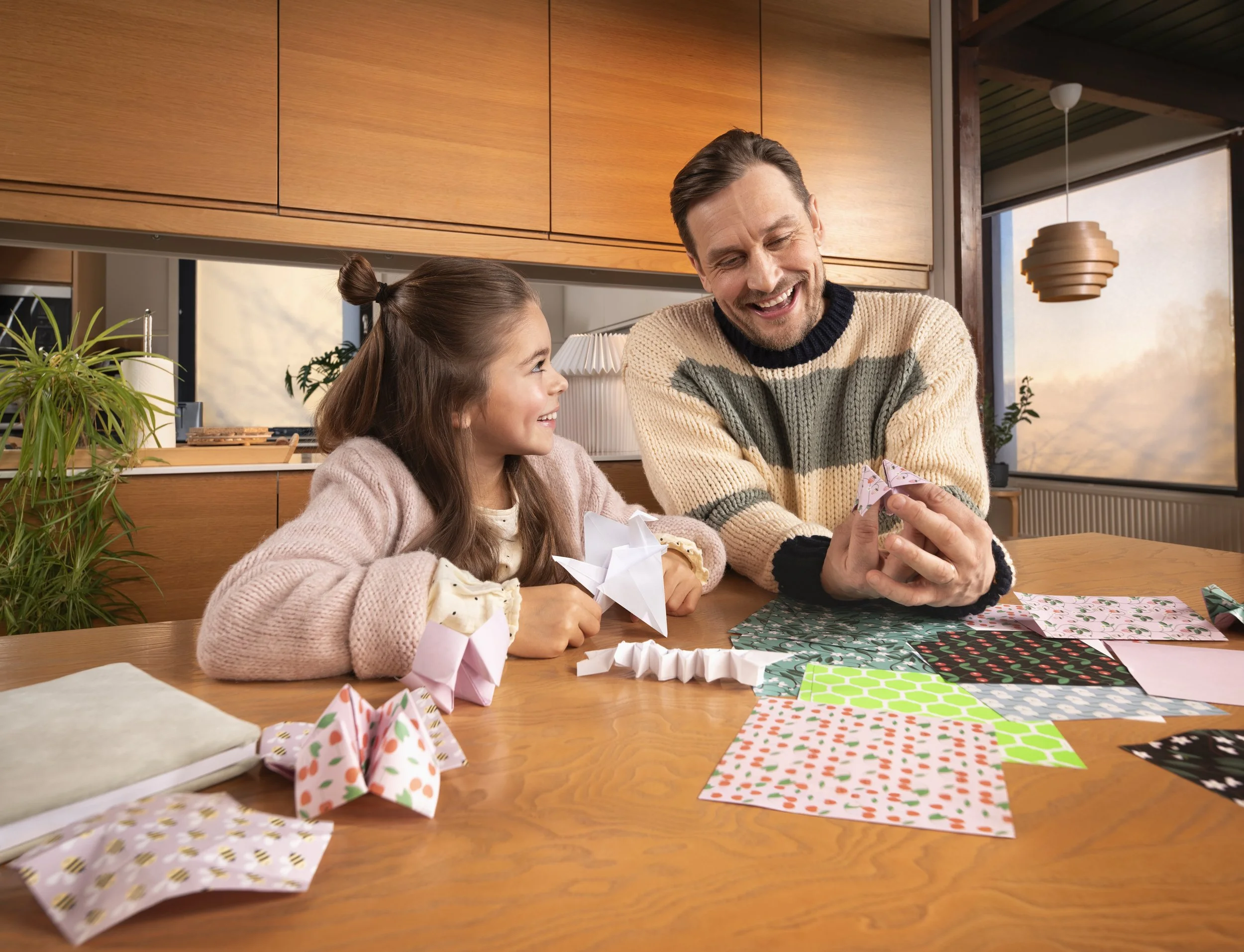 man and girl doing origami on kitchen table