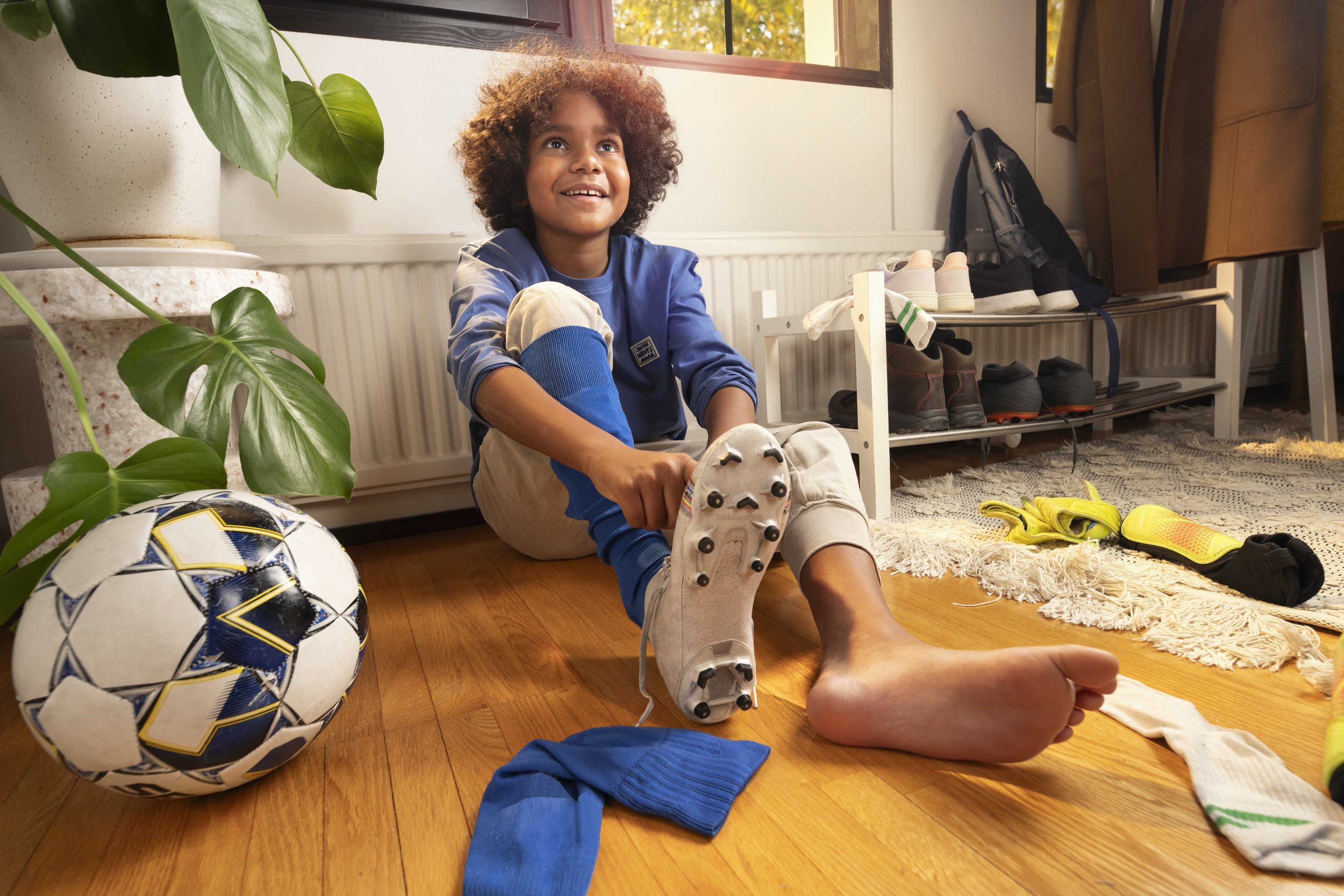 boy putting on futbal gear on floor. brand photography
