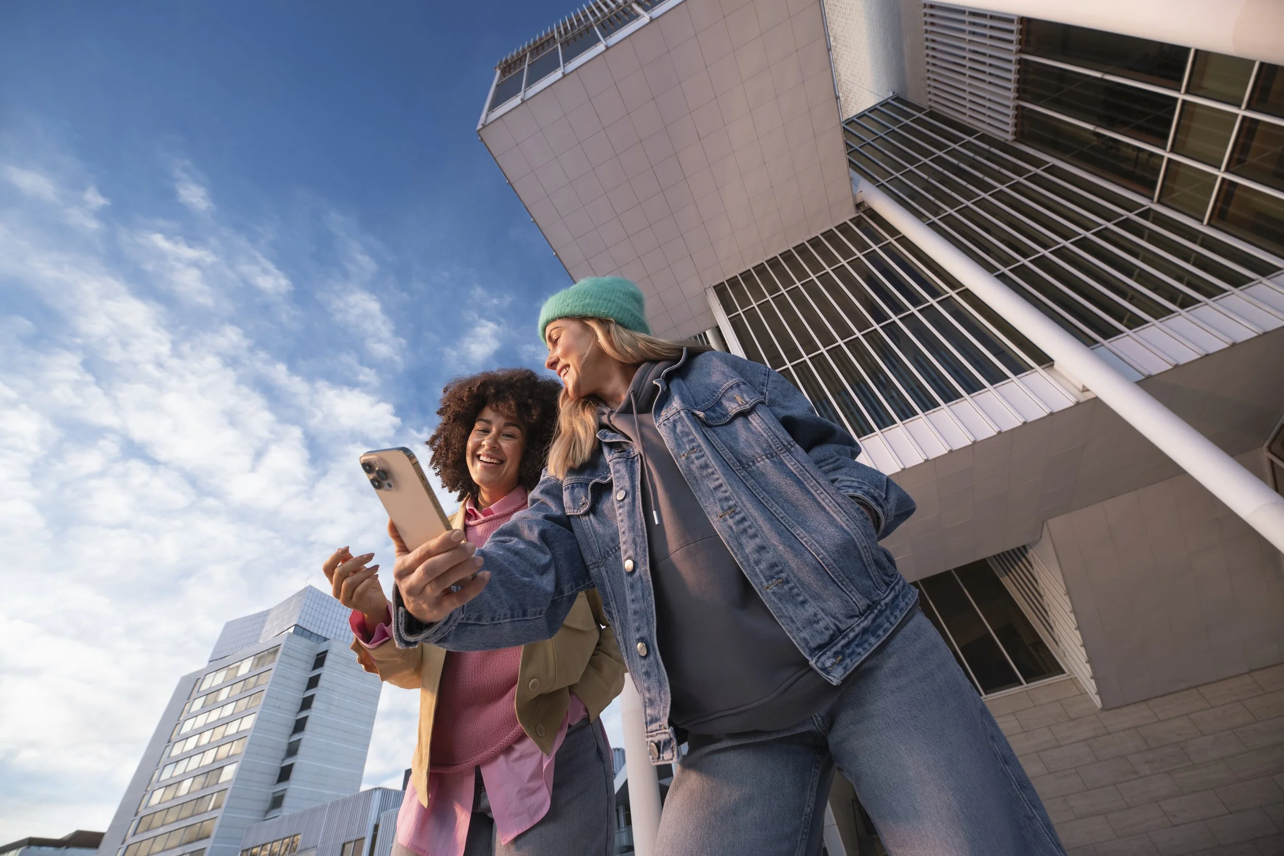 two women taking a selfie outside in autum with blue sky. brand phography