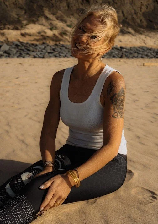 Kaja sitzt nach dem Yoga entspannt im Sand