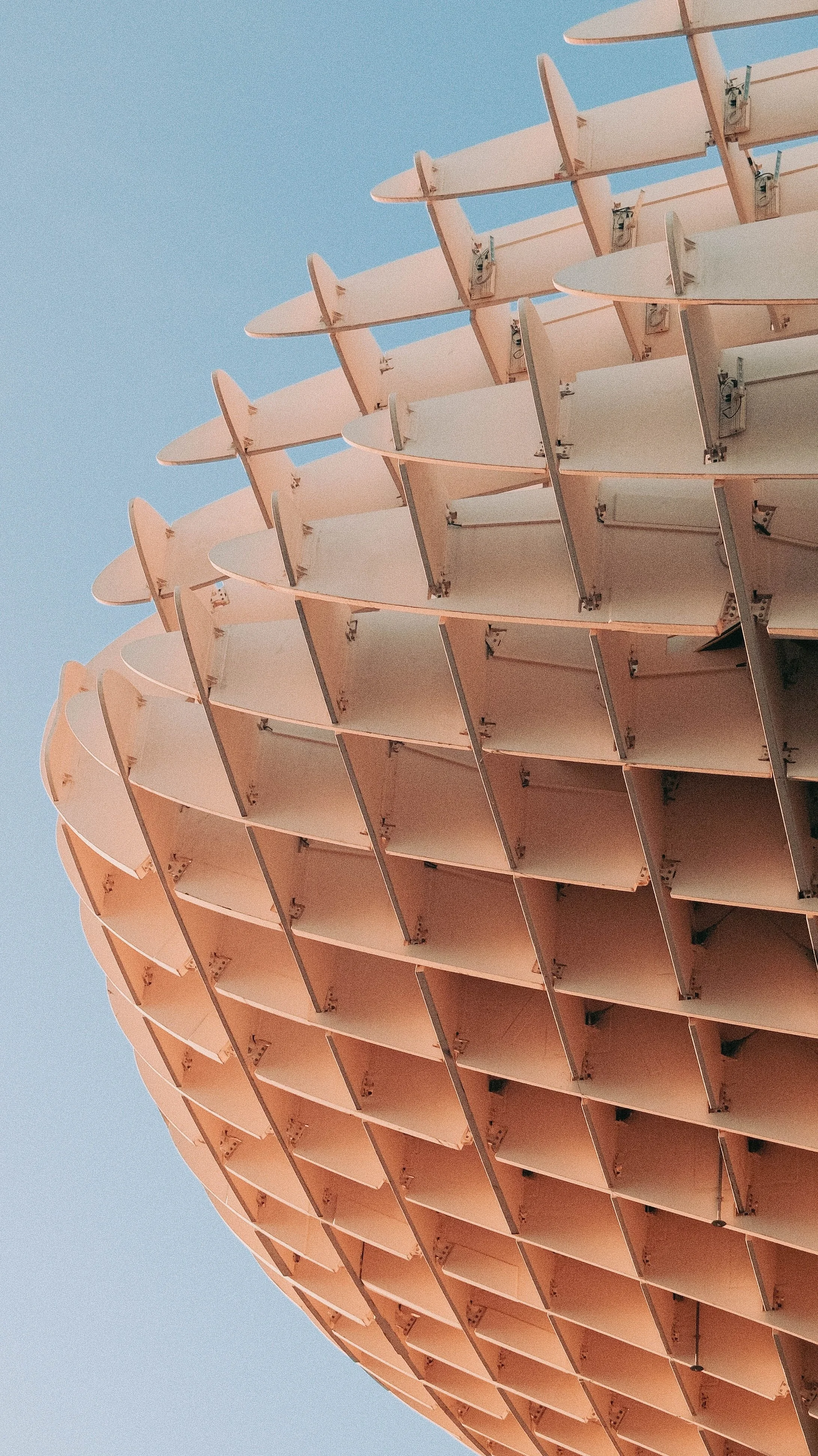 Close-up of a row of pink architectural sunshades or canopies with a clear blue sky in the background.