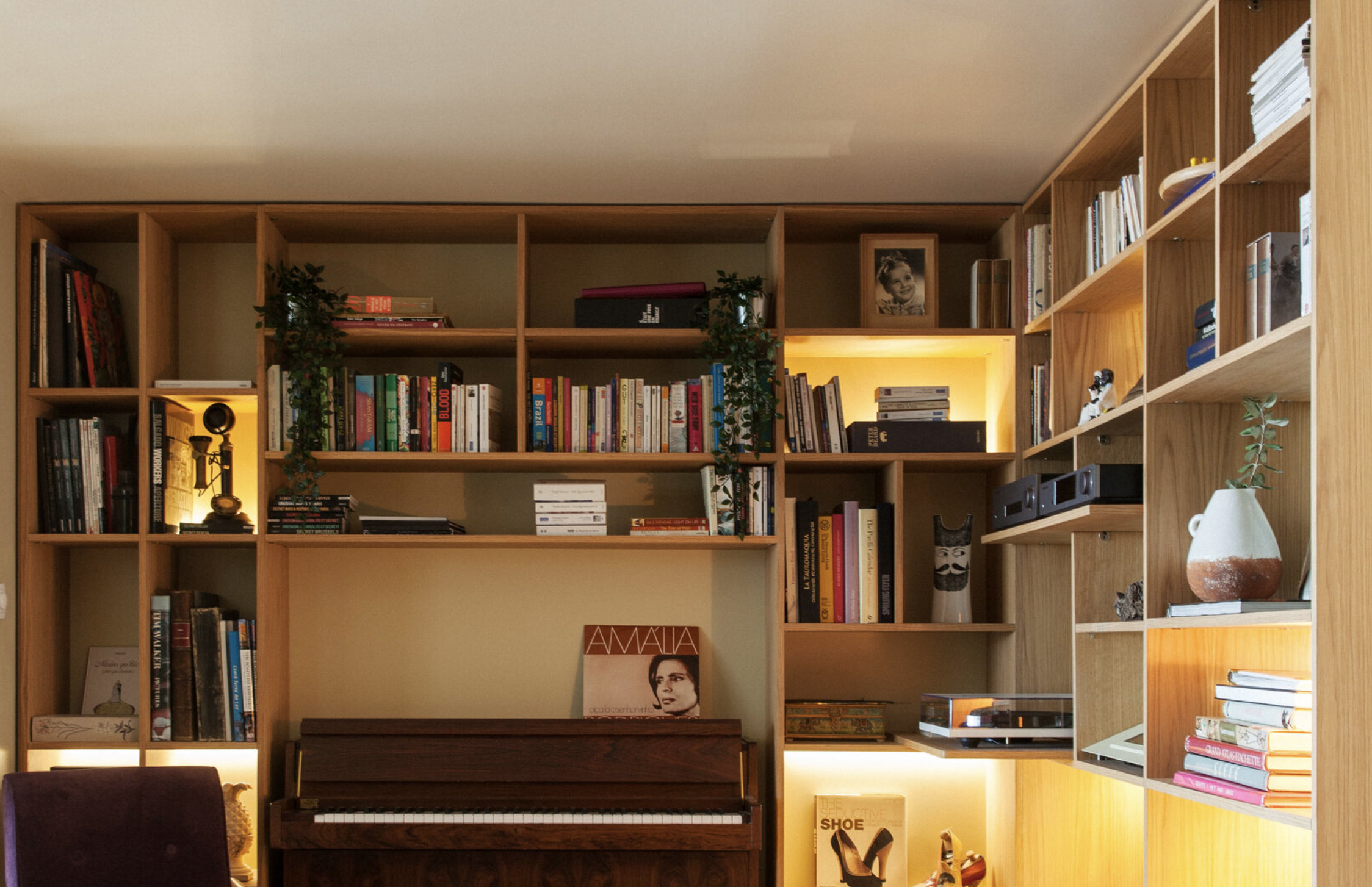 Wooden bookshelf filled with books, photos, and decorative items in a cozy living space.