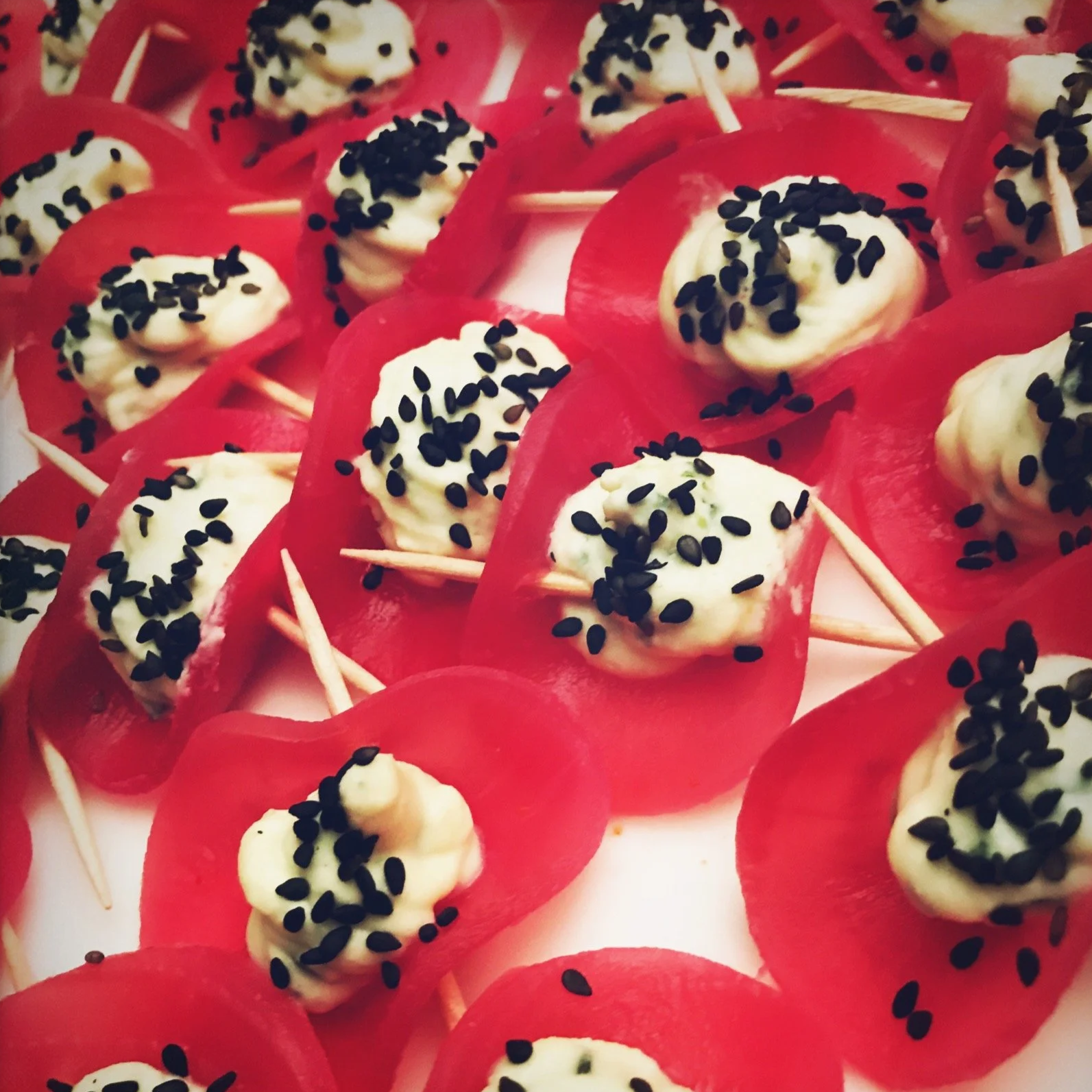 Bonbons rouges avec une garniture blanche et des graines de sésame noires.